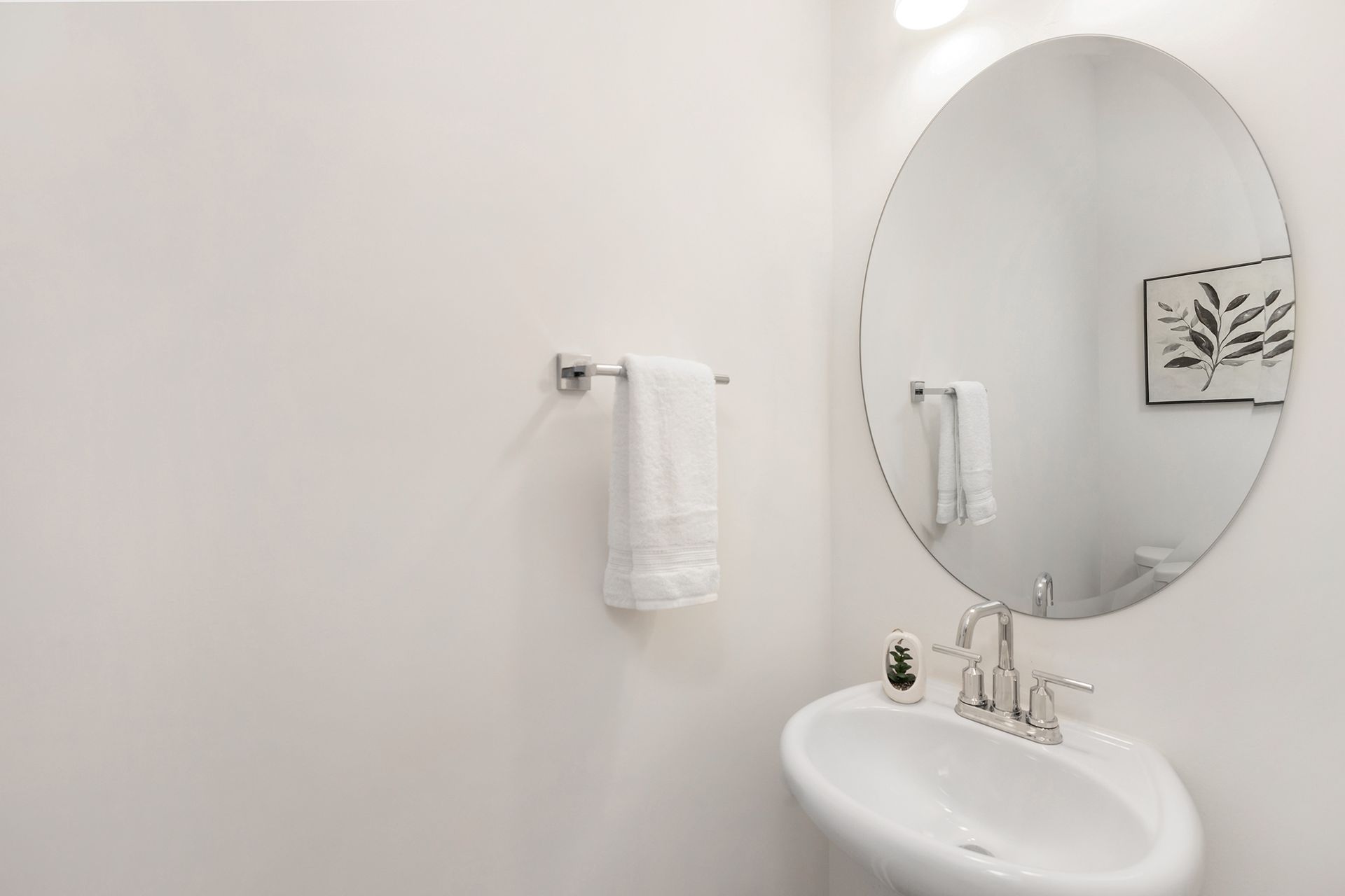 A bathroom with a sink and a round mirror.