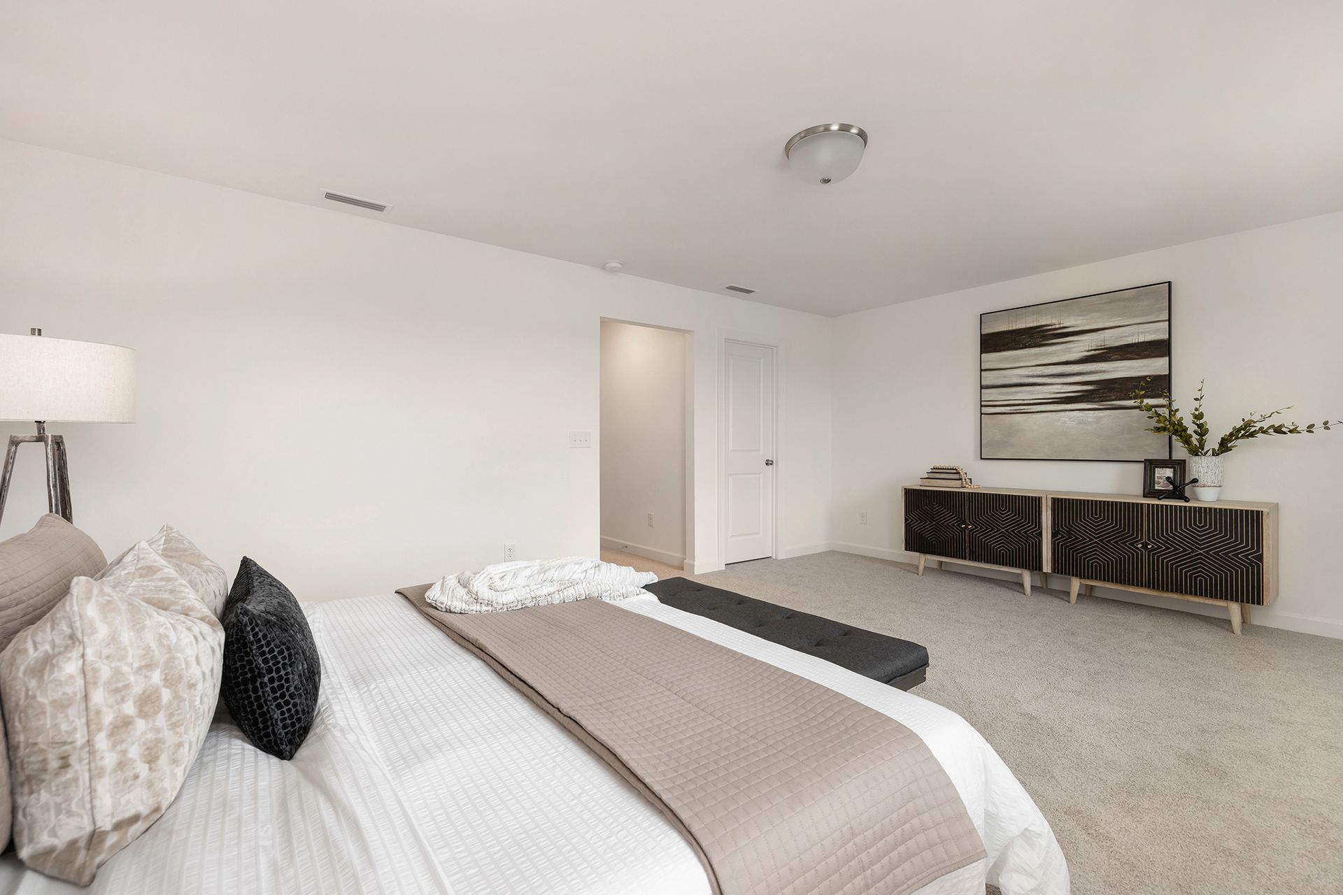 A bedroom with a large bed and a painting on the wall.