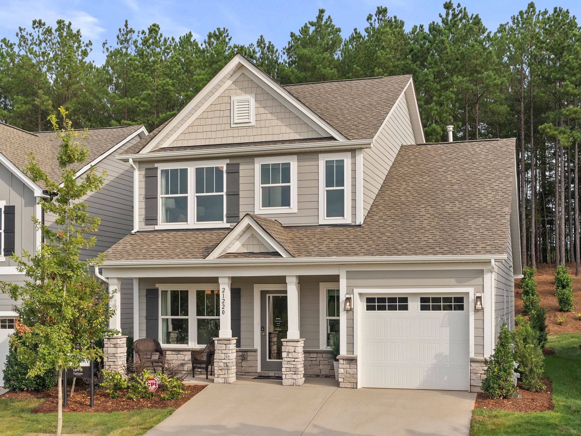 A large house with a white garage door is surrounded by trees.