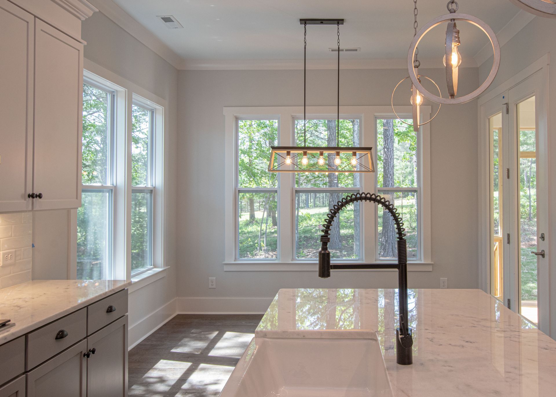 A kitchen with a sink , cabinets , and windows.