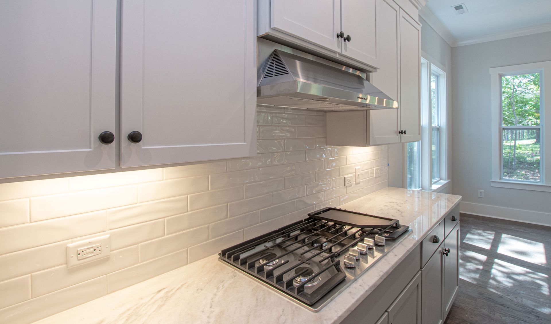 A kitchen with white cabinets and a stove top oven.