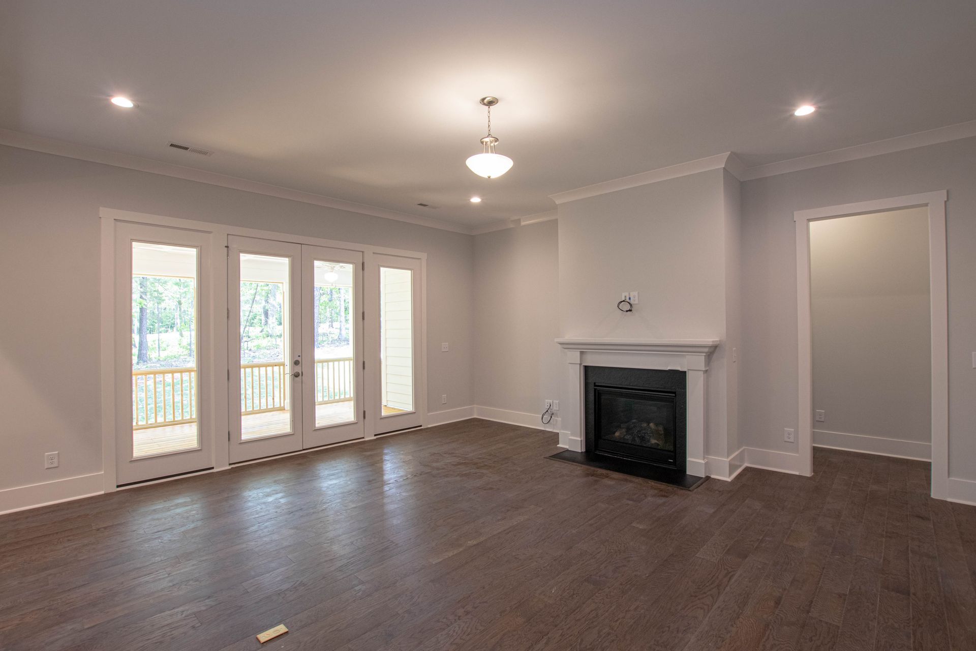 An empty living room with a fireplace and sliding glass doors.