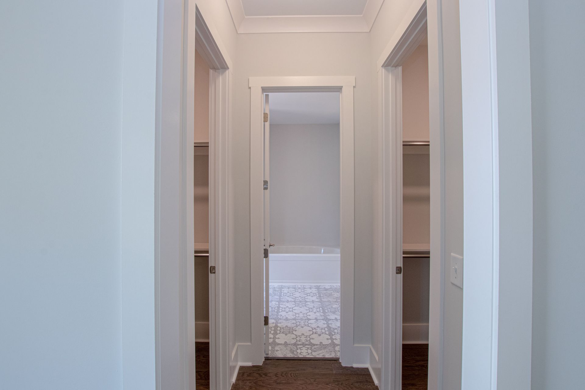 A hallway in a house leading to a bathroom and a bedroom.