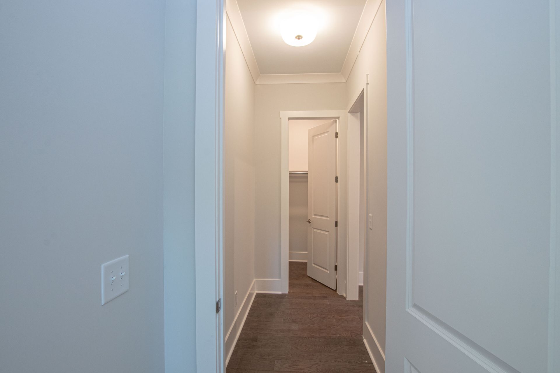 A hallway in a house with a door open and a light on the ceiling.