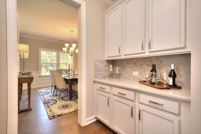 A kitchen with white cabinets and a bottle of wine on the counter.