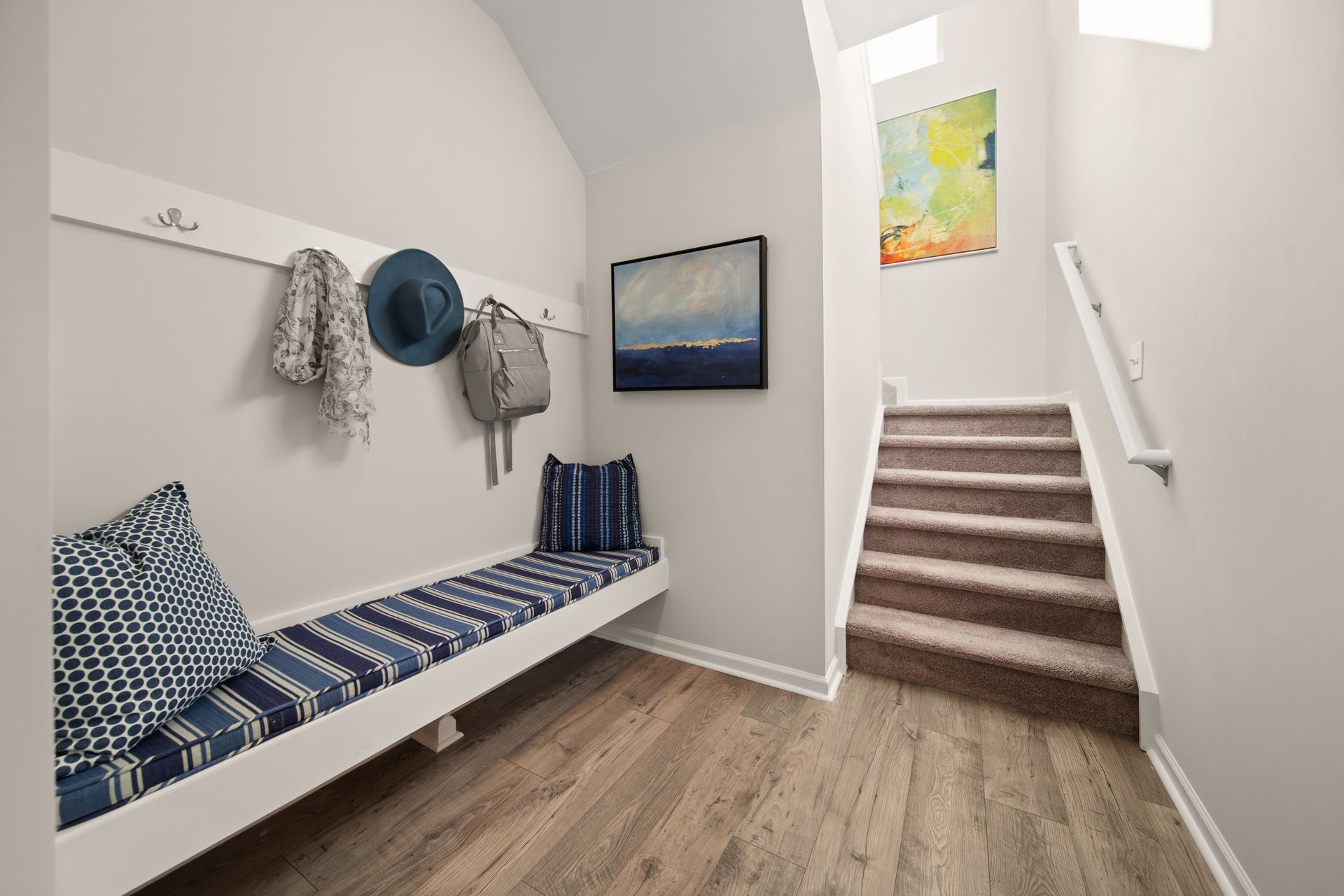 A hallway with a bench and stairs leading up to the second floor.