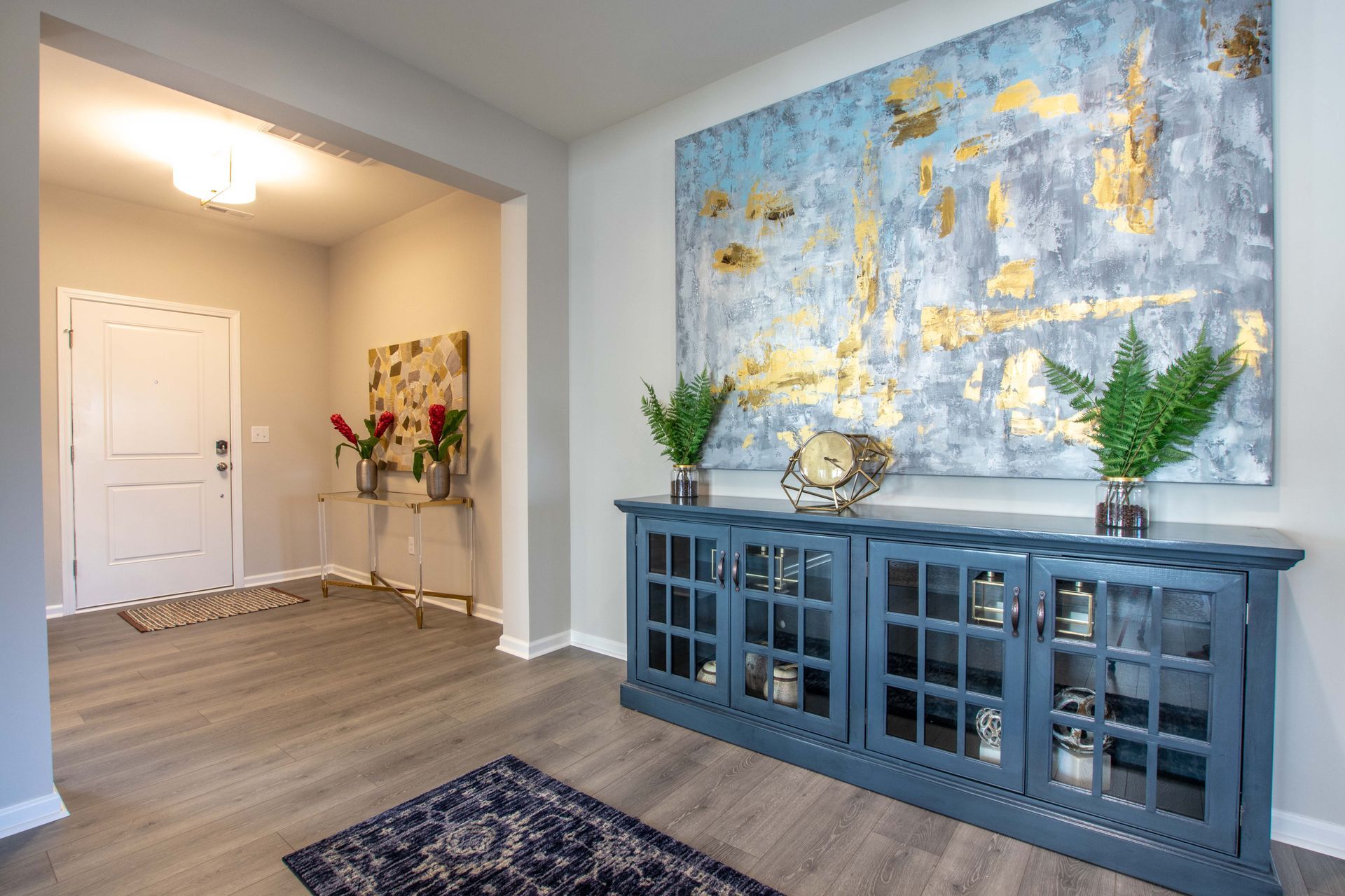 A living room with a large painting on the wall and a blue cabinet.