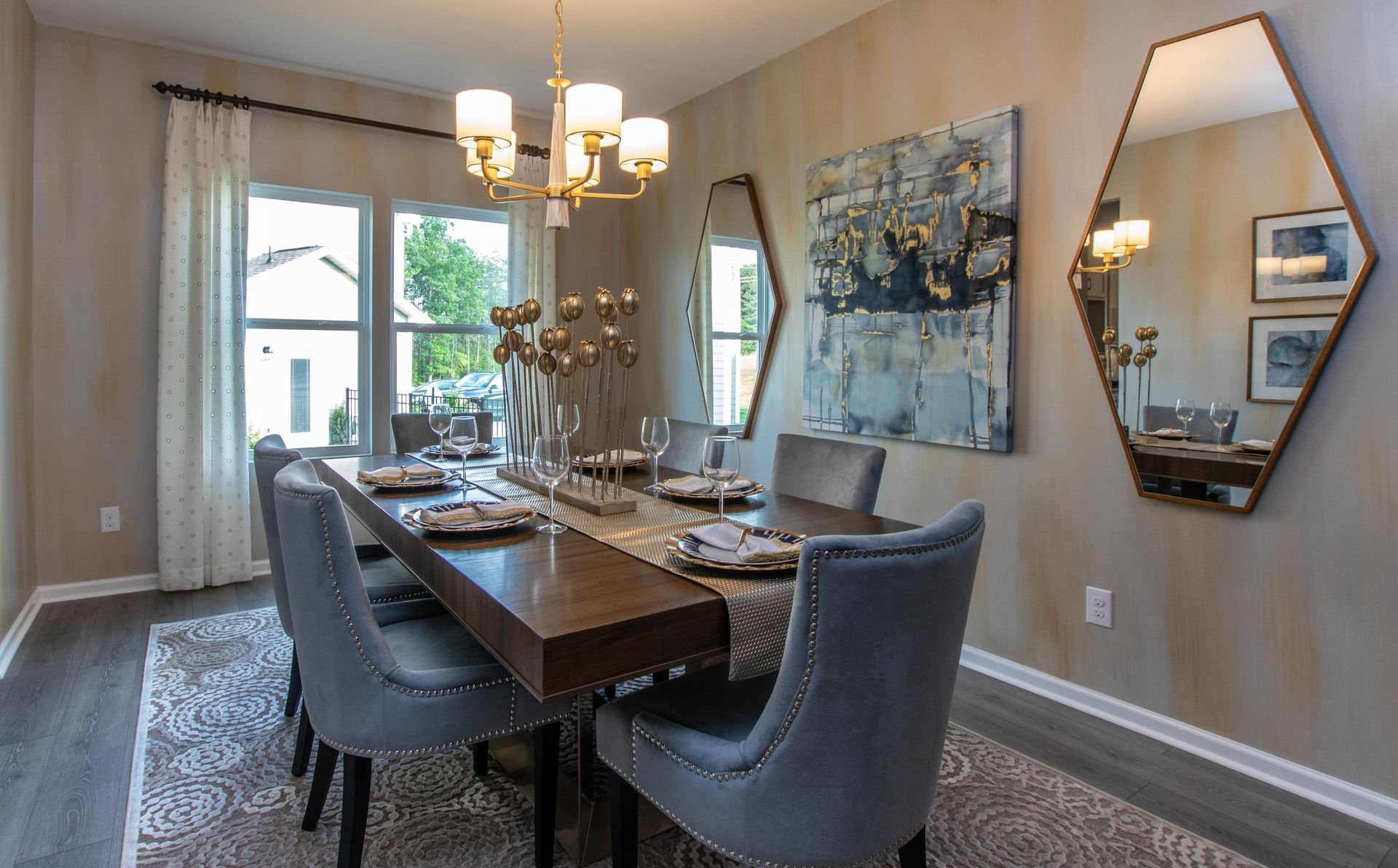 A dining room with a long table and chairs and two mirrors on the wall.