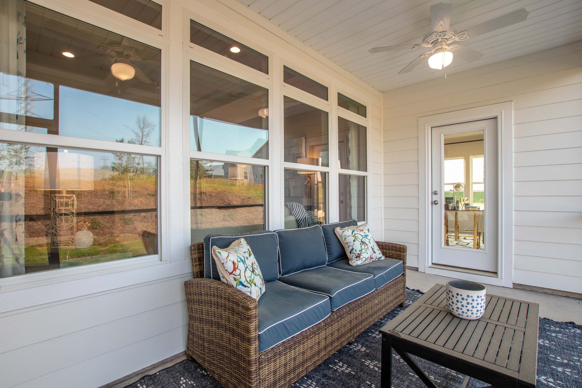 There is a couch and a table on the porch of a house.