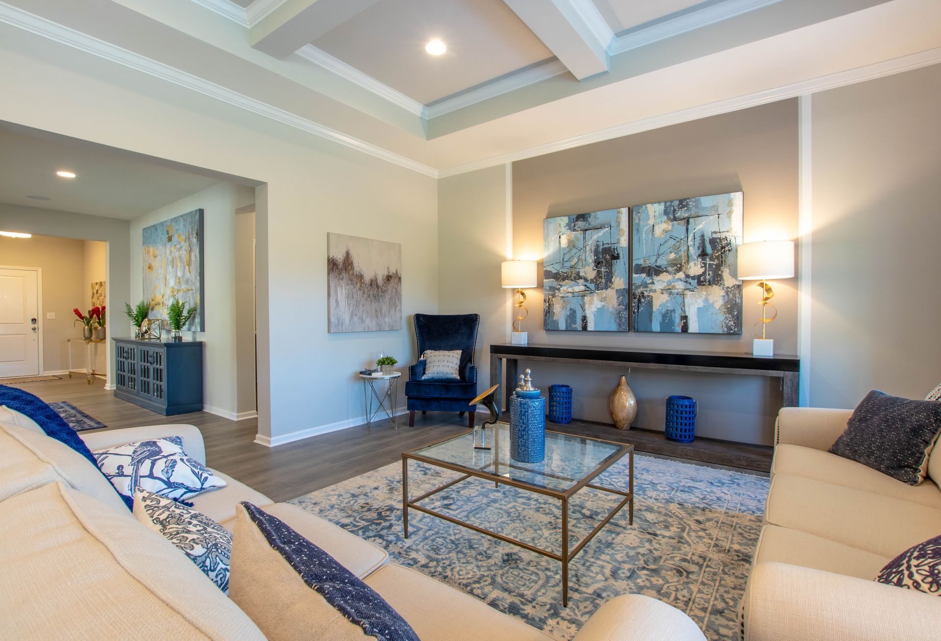 A living room with a couch , chair , coffee table and paintings on the wall.