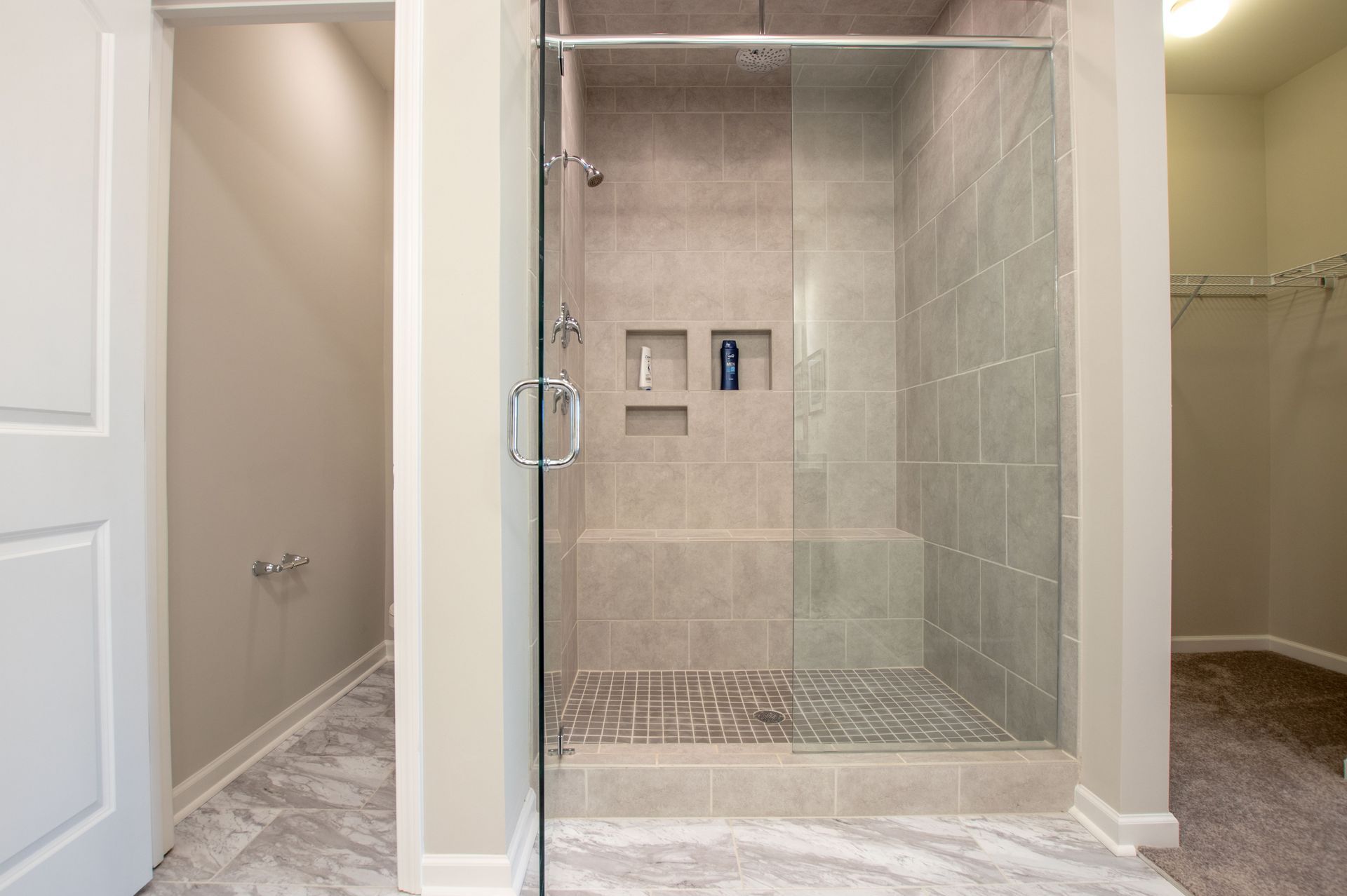 A walk in shower with a glass door in a bathroom.