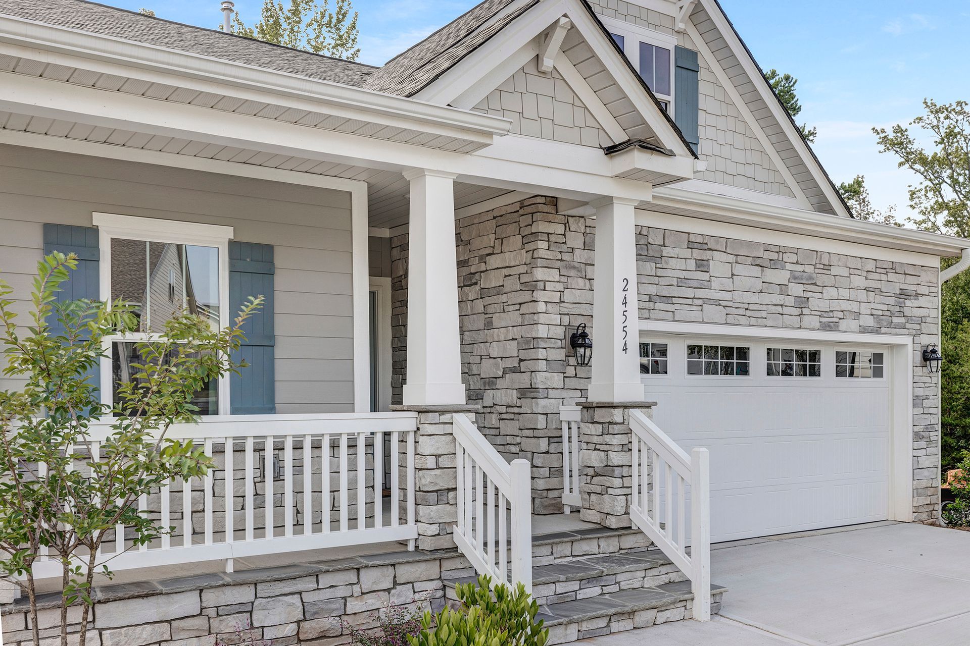 A white house with a large porch and a white garage door.