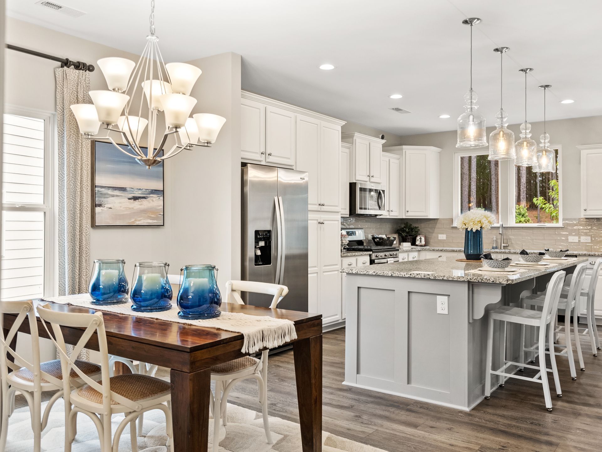 A kitchen and dining room in a model home with a table and chairs.