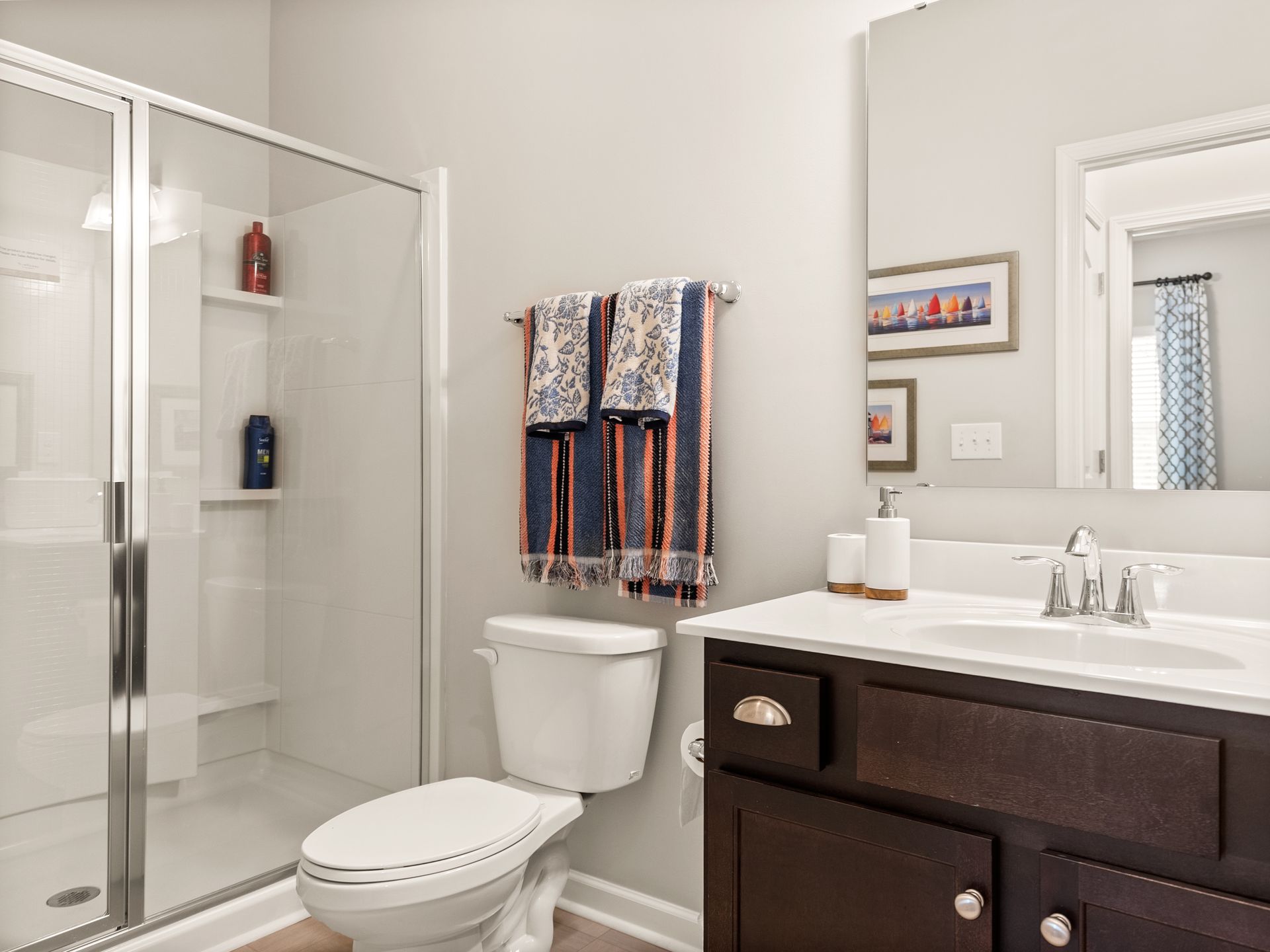 A bathroom with a toilet , sink , shower and mirror.