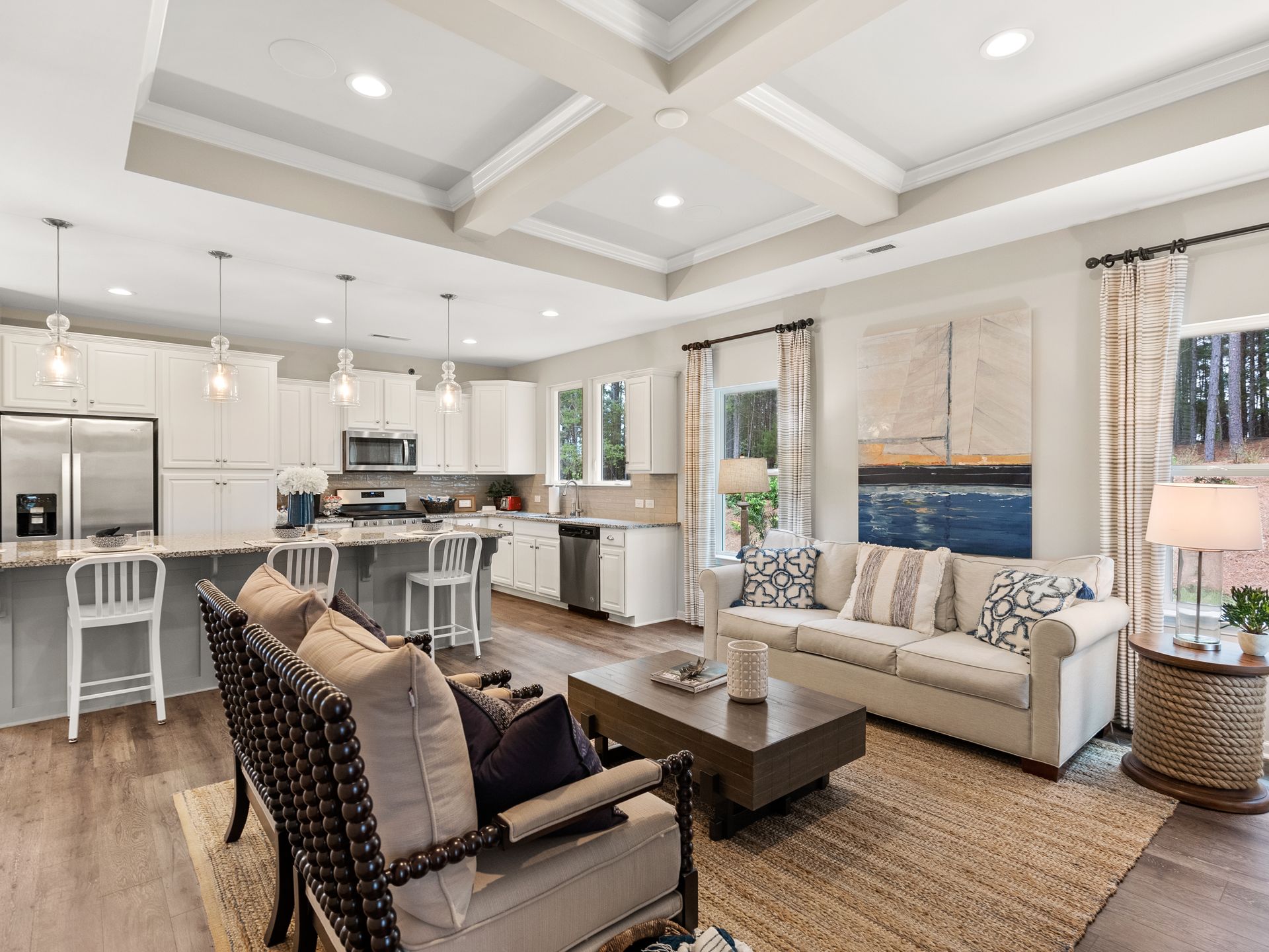 A living room with a couch , chairs , a coffee table and a kitchen.