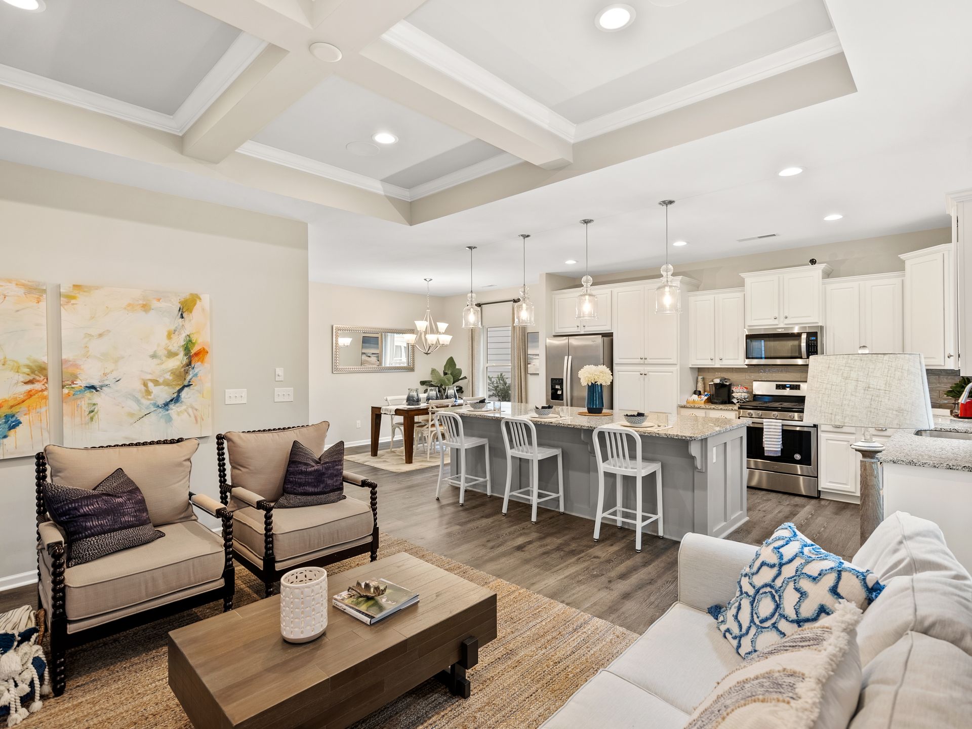A living room with a couch , chairs , a coffee table and a kitchen.