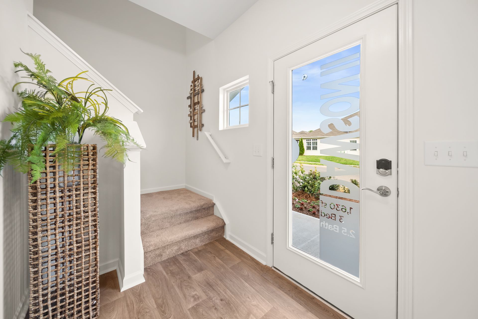 A hallway with stairs and a door with a glass door.