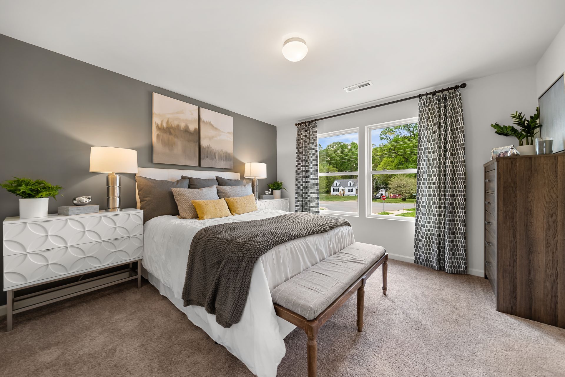 A bedroom with a bed , nightstand , dresser and window.