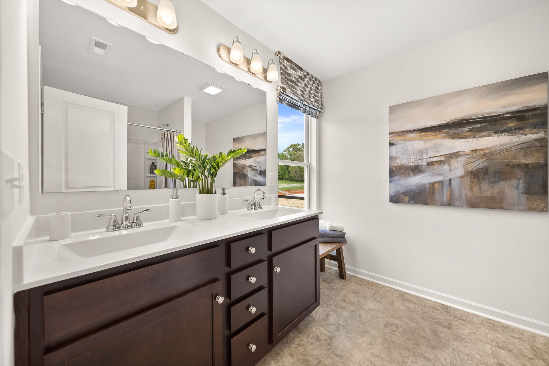 A bathroom with two sinks , a large mirror and a painting on the wall.