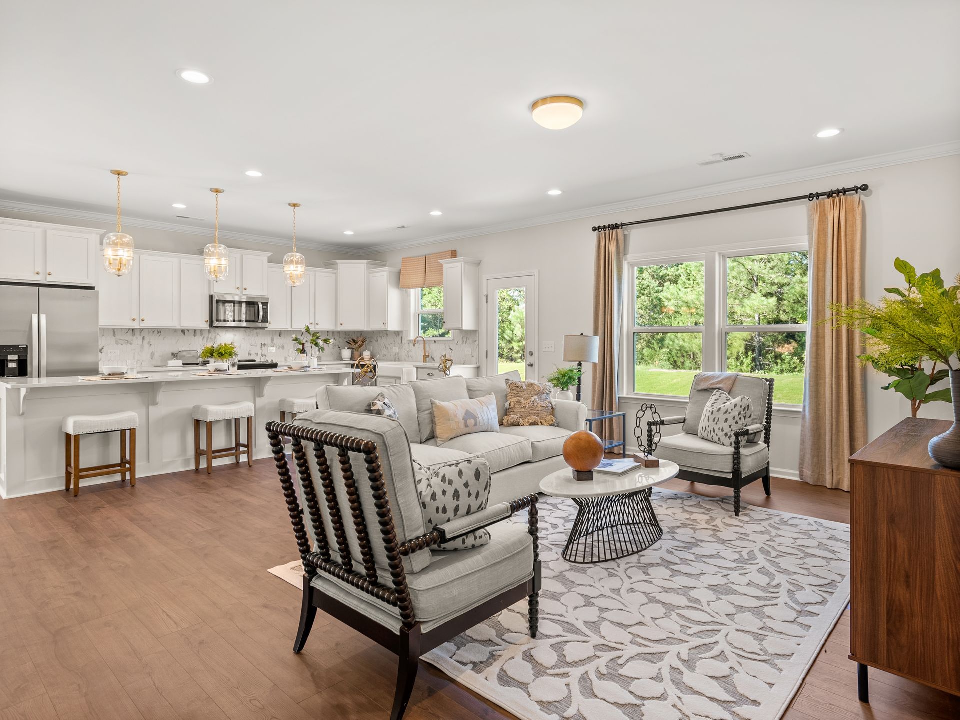 A living room with a couch , chairs , a table and a rug.