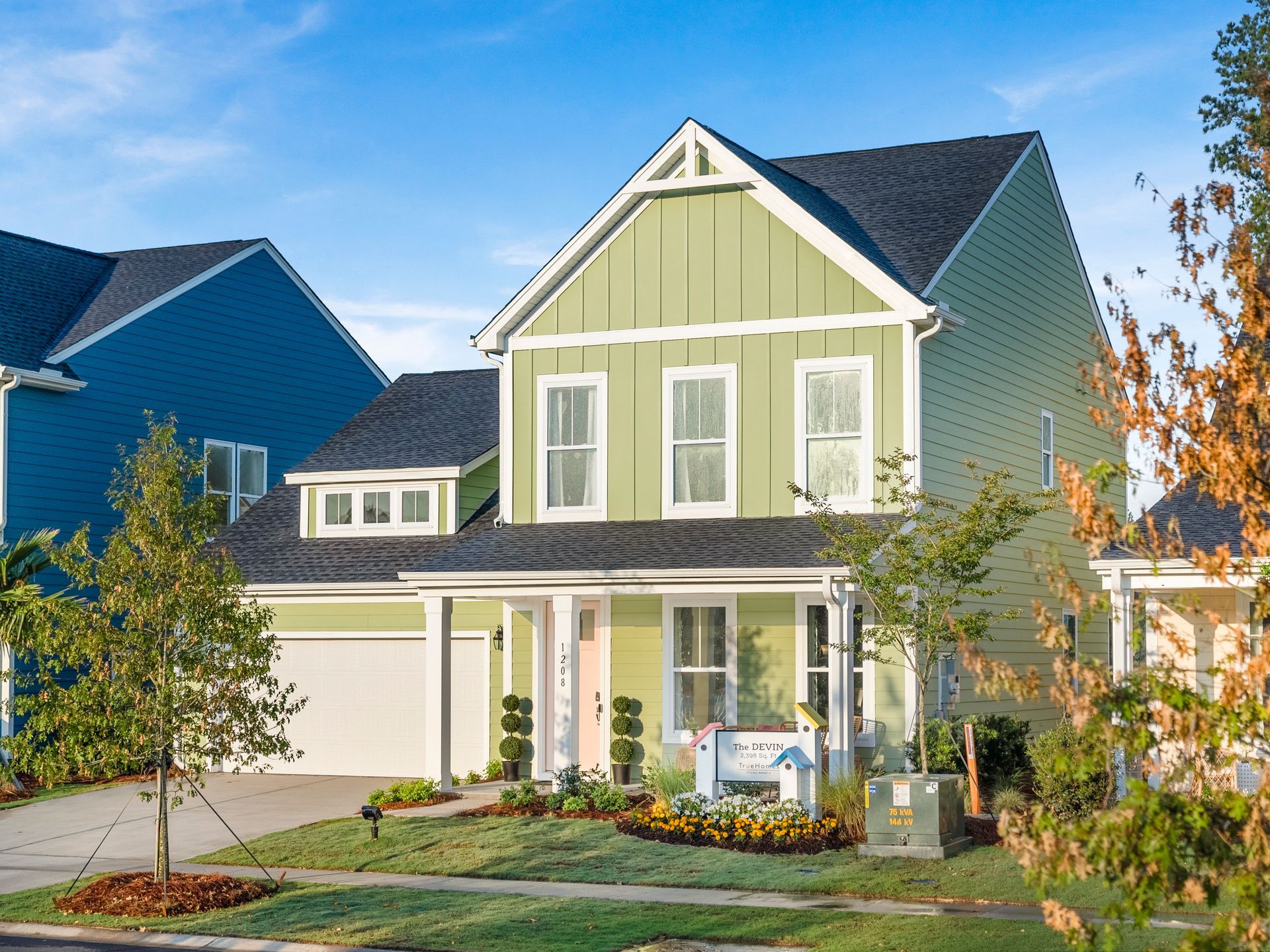 A green and white house with a blue house in the background.