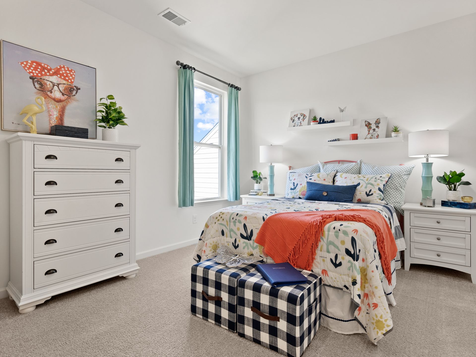 A bedroom with a bed , dresser , nightstand and ottoman.