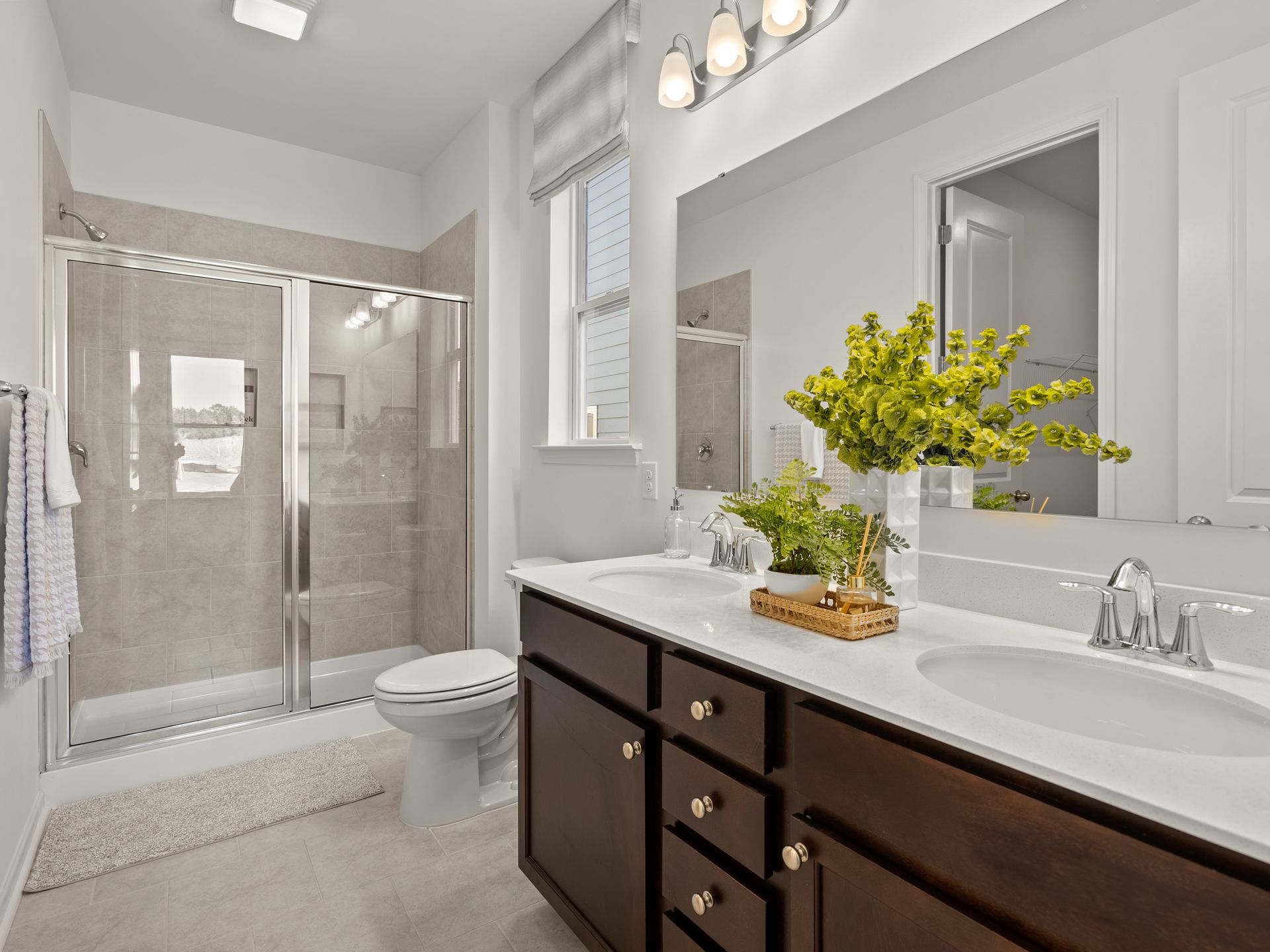 A bathroom with two sinks , a toilet , and a shower.