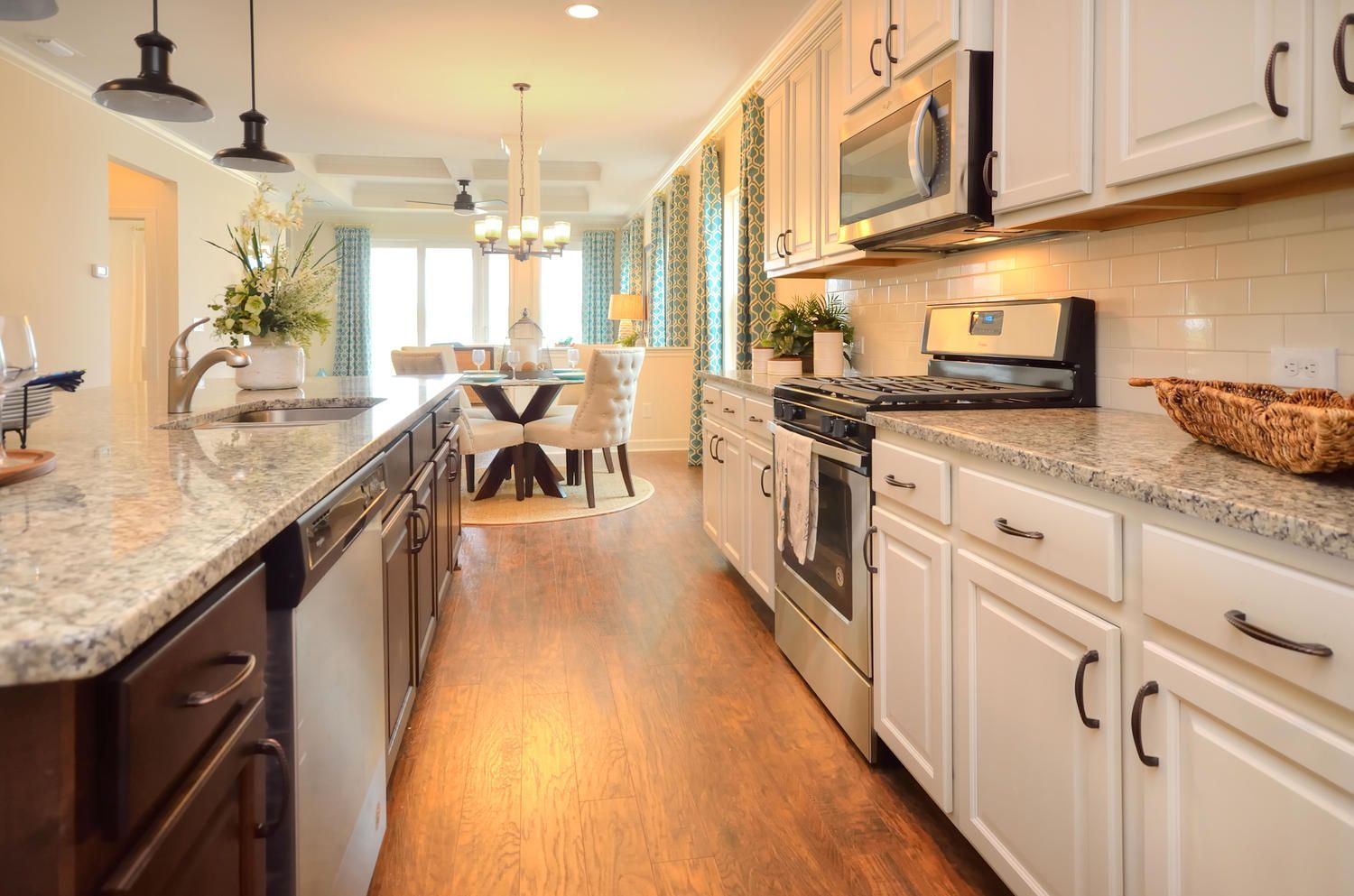 A kitchen with white cabinets , granite counter tops , stainless steel appliances and a dining room in the background.