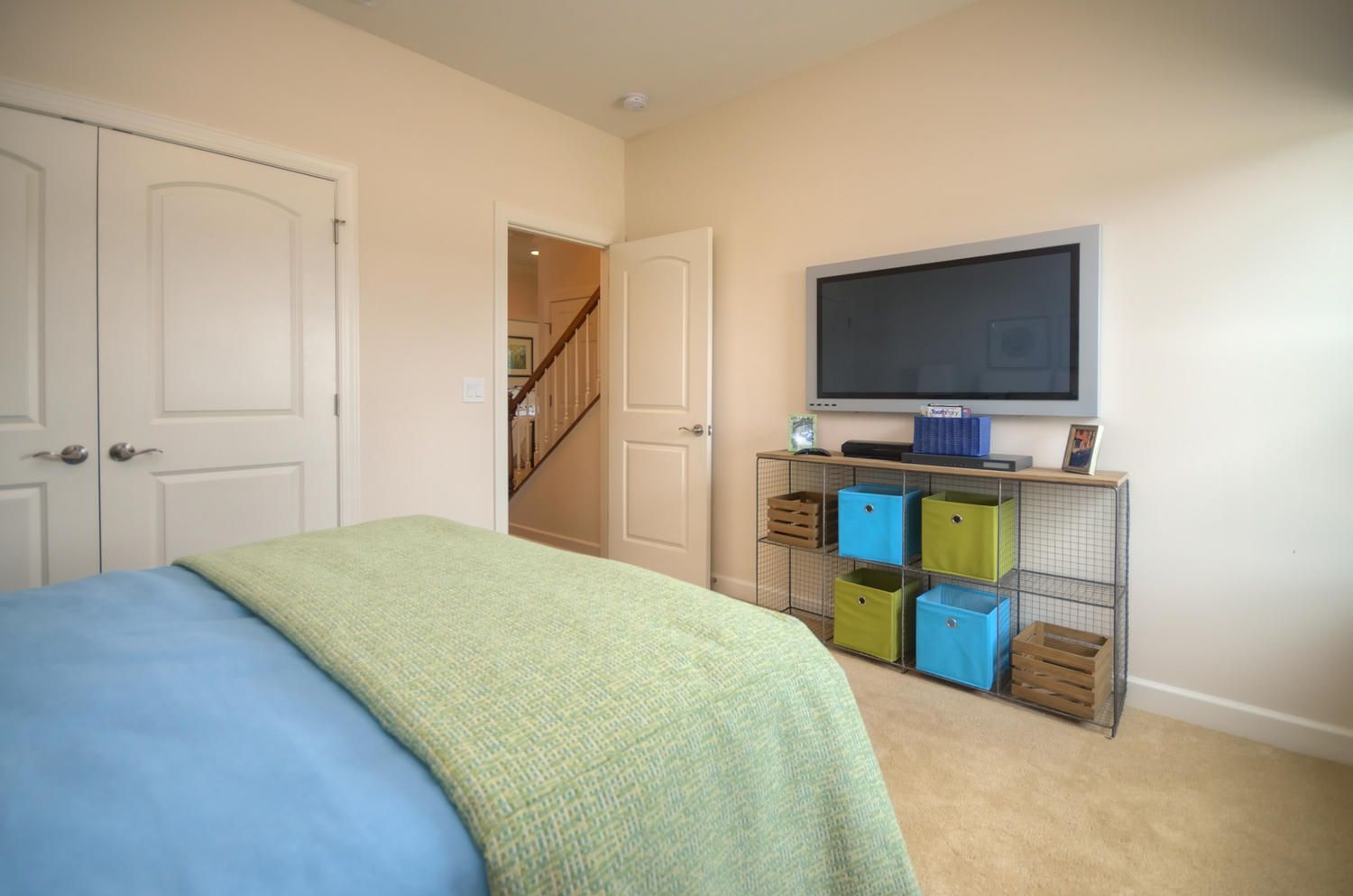 A bedroom with a bed and a flat screen tv on the wall.