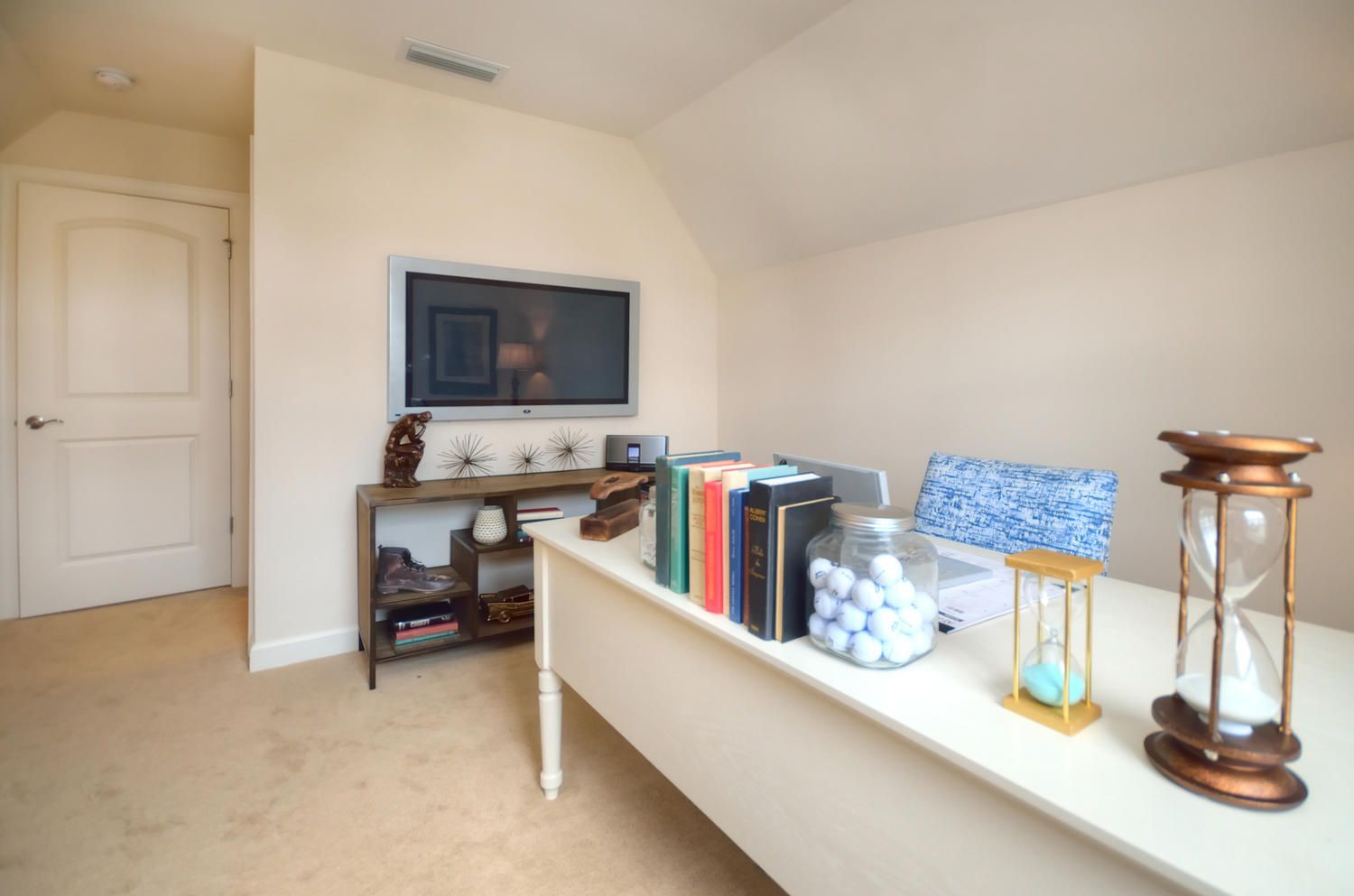 A room with a desk and a television on the wall