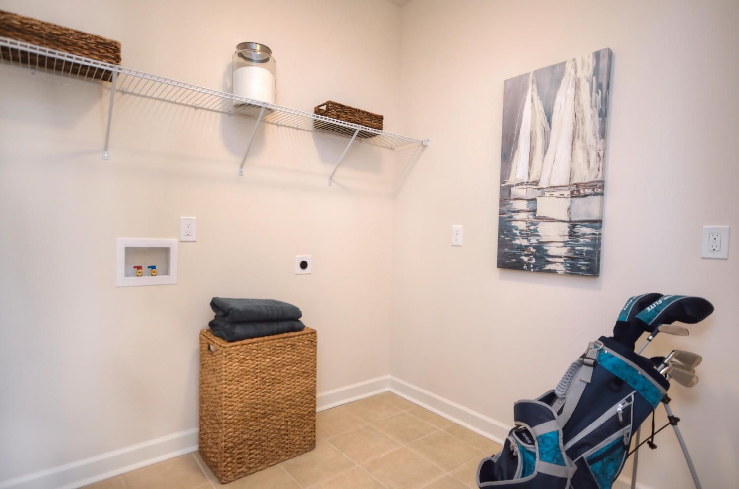 A laundry room with a golf bag and a painting on the wall.