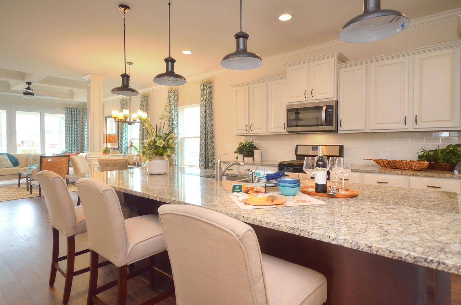 A kitchen with white cabinets , granite counter tops , stainless steel appliances and a large island.