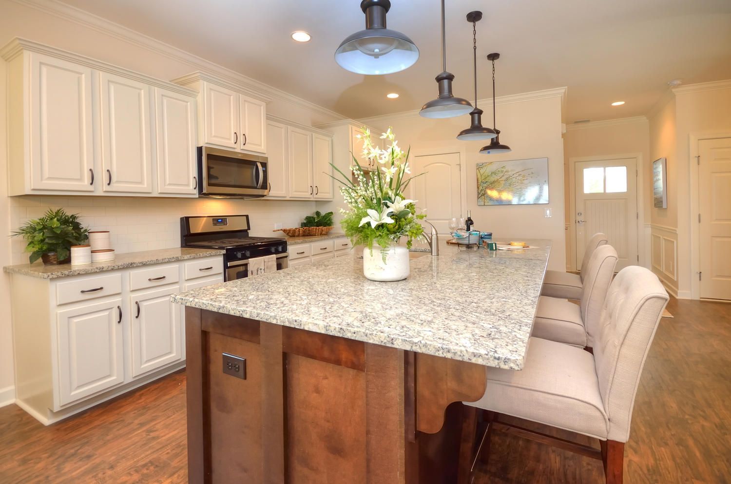 A kitchen with white cabinets , granite counter tops , and a large island.