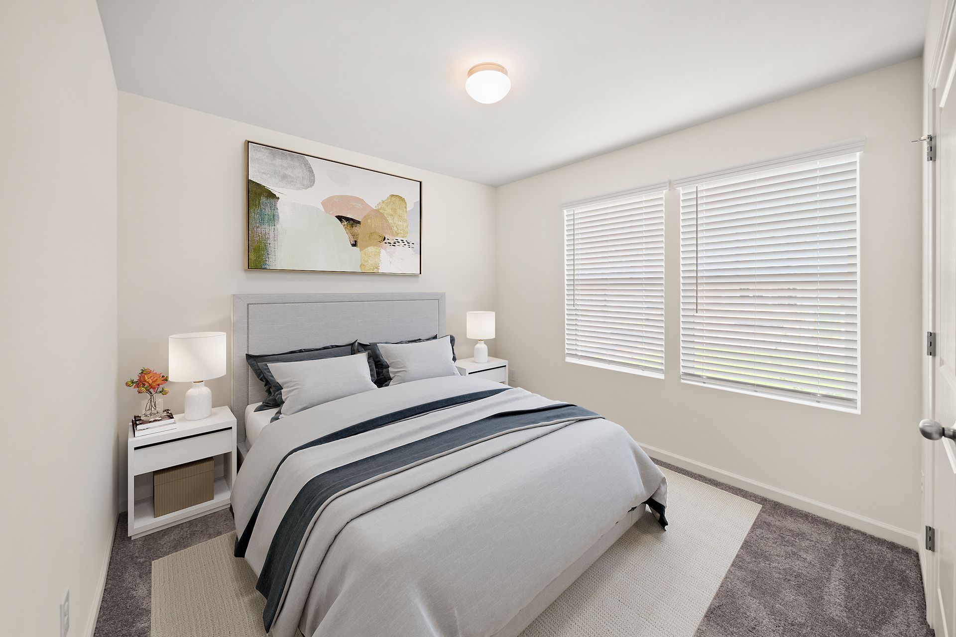 A bedroom with a large bed and two windows.