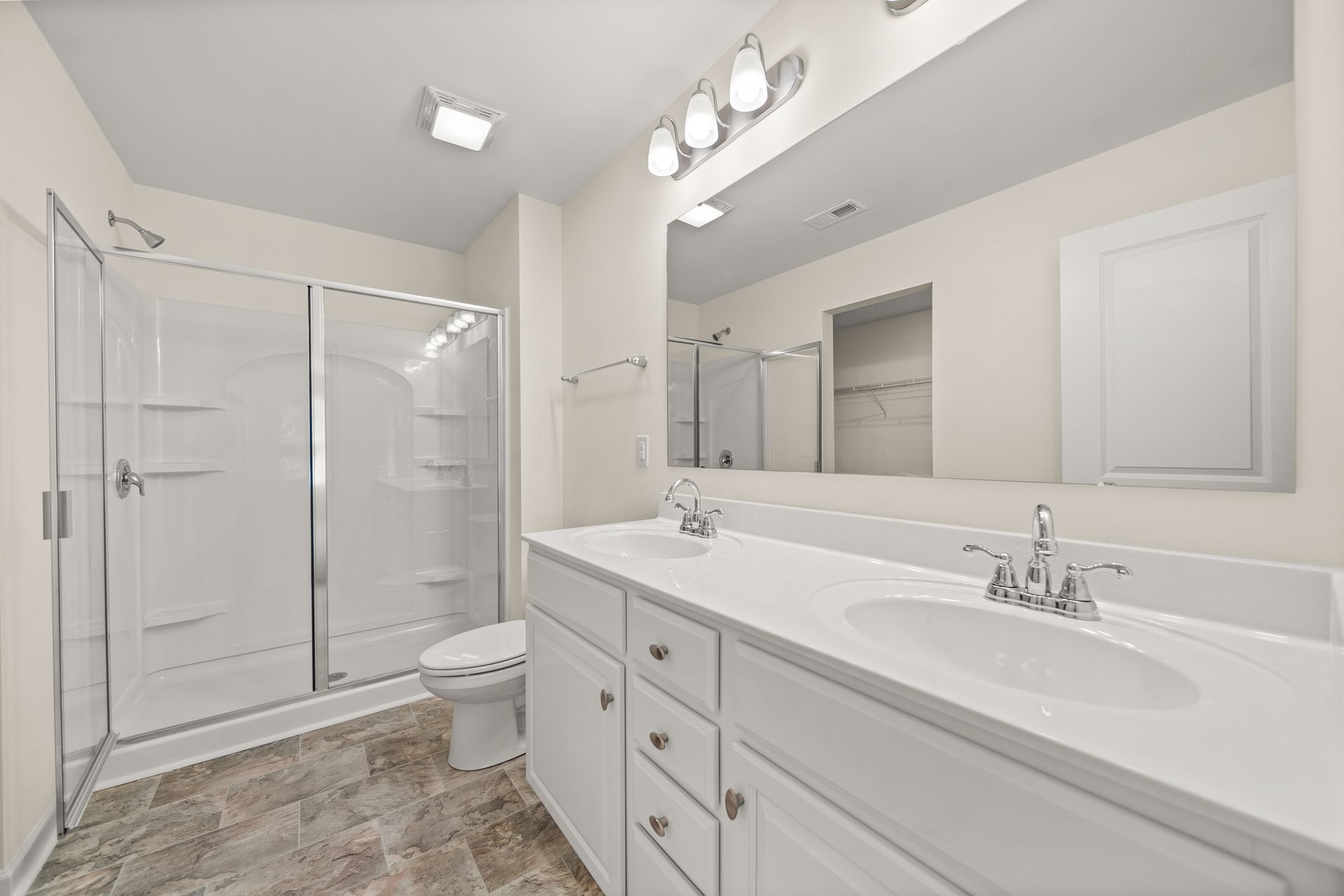 A bathroom with two sinks , a toilet , and a shower.