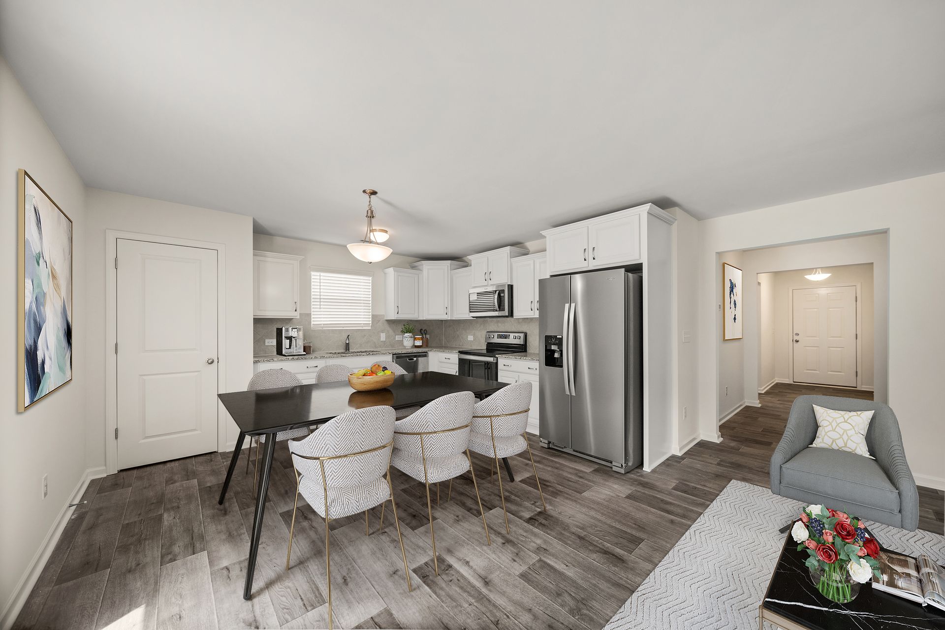 A living room with a dining table , chairs , and a refrigerator.