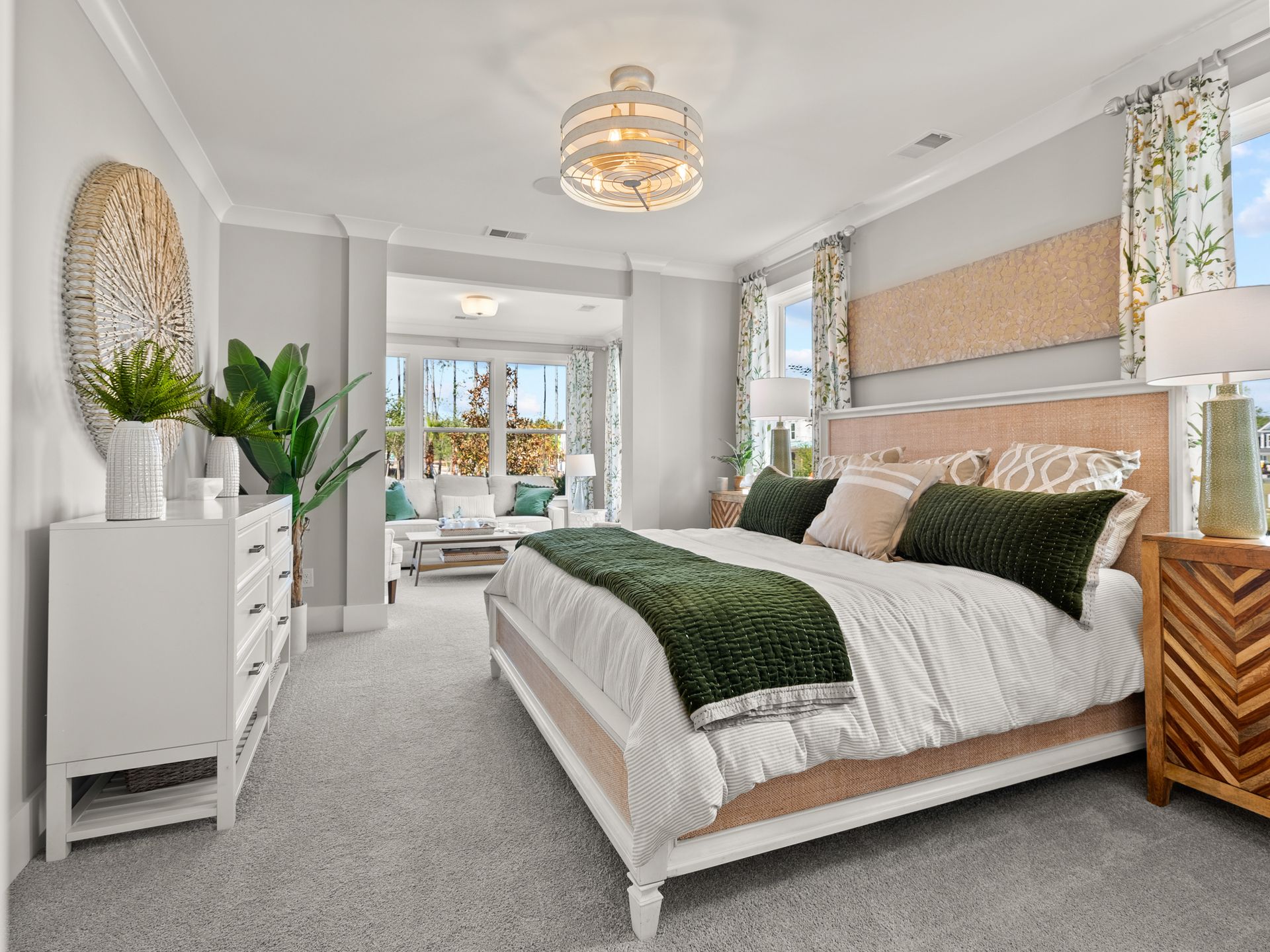 A bedroom with a king size bed , dresser , nightstand , and chandelier.