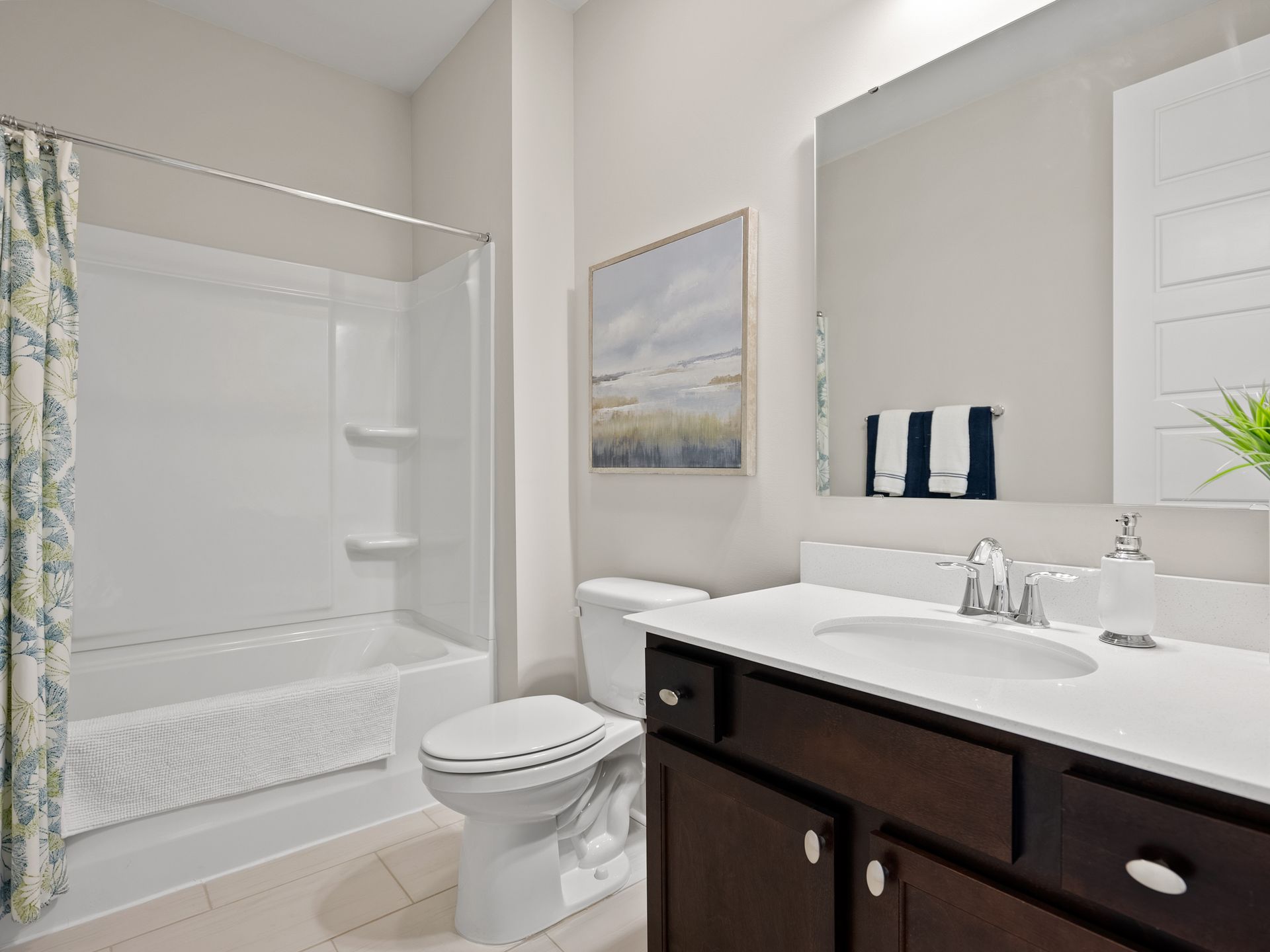 A bathroom with a toilet , sink , tub and mirror.