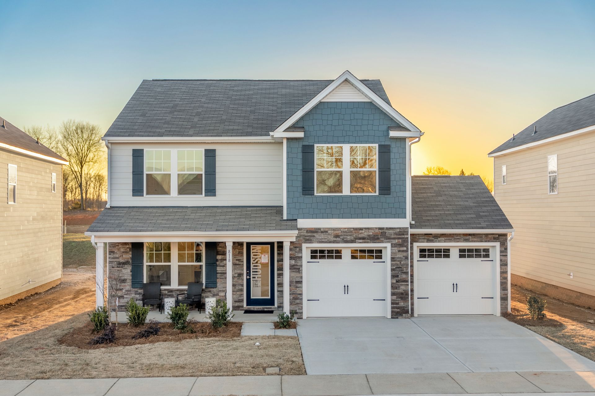 A large blue and white house with two garages and a porch.