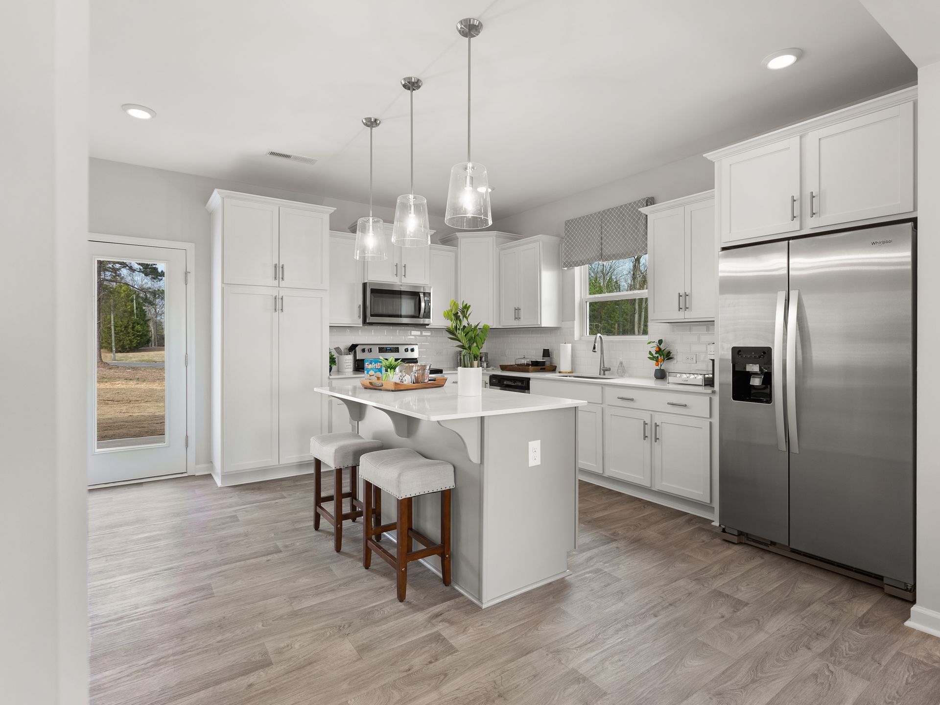 A kitchen with white cabinets , stainless steel appliances , and a large island.