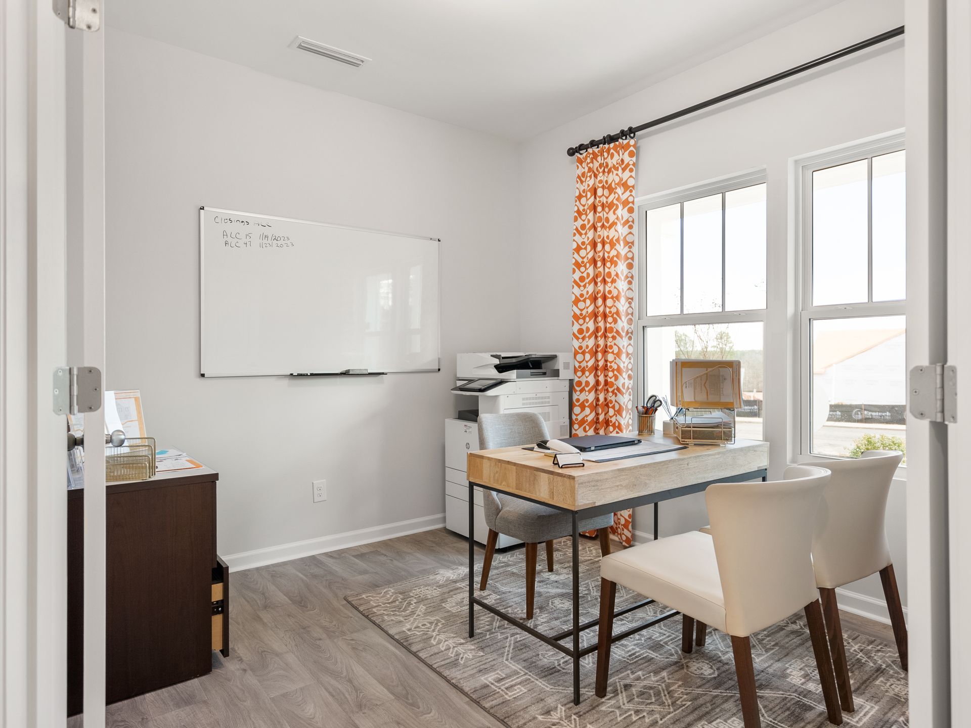 A home office with a desk , chairs , and a whiteboard.