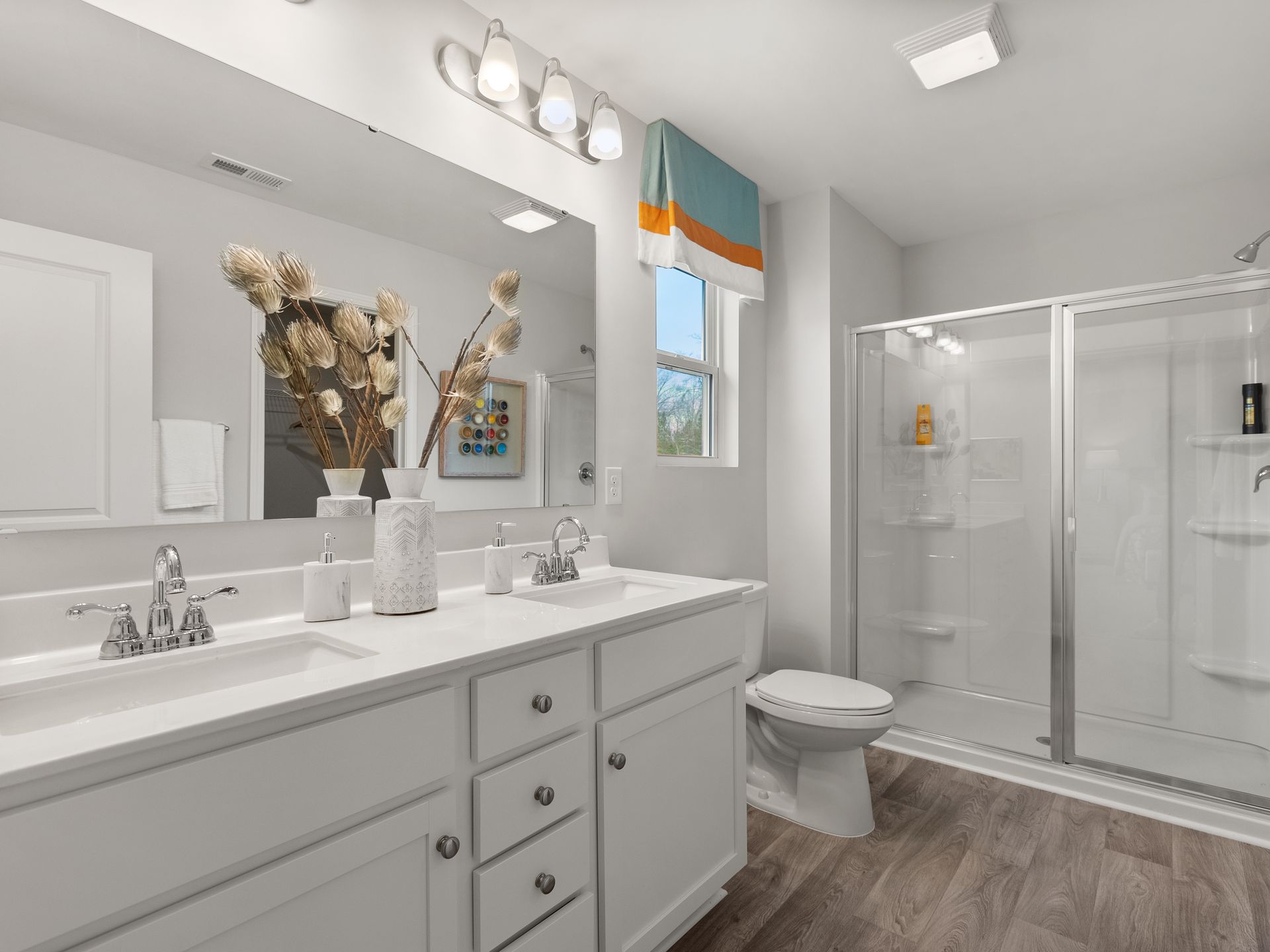 A bathroom with a toilet , sink , mirror and shower.