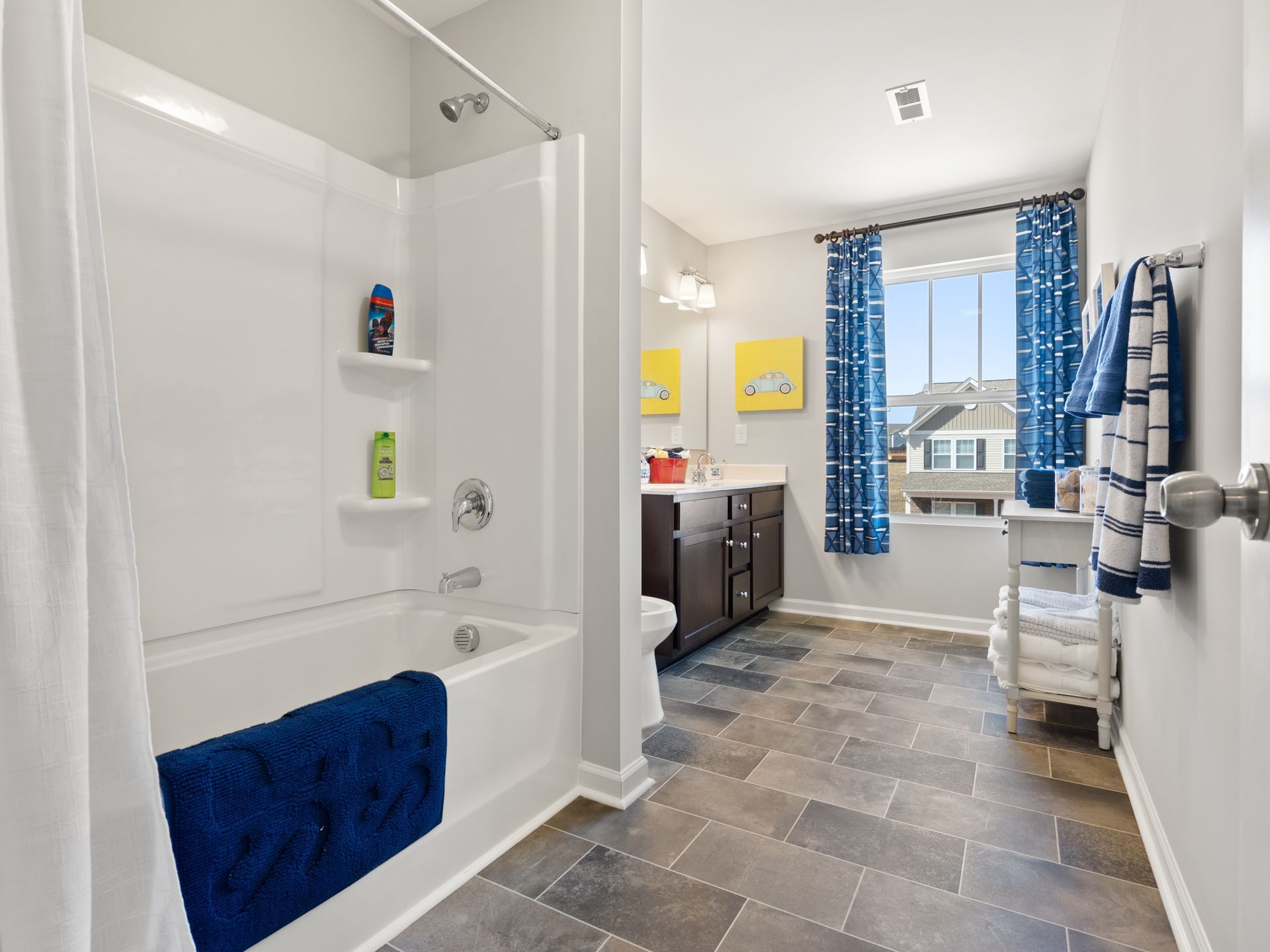 A bathroom with a bathtub , toilet , sink and window.