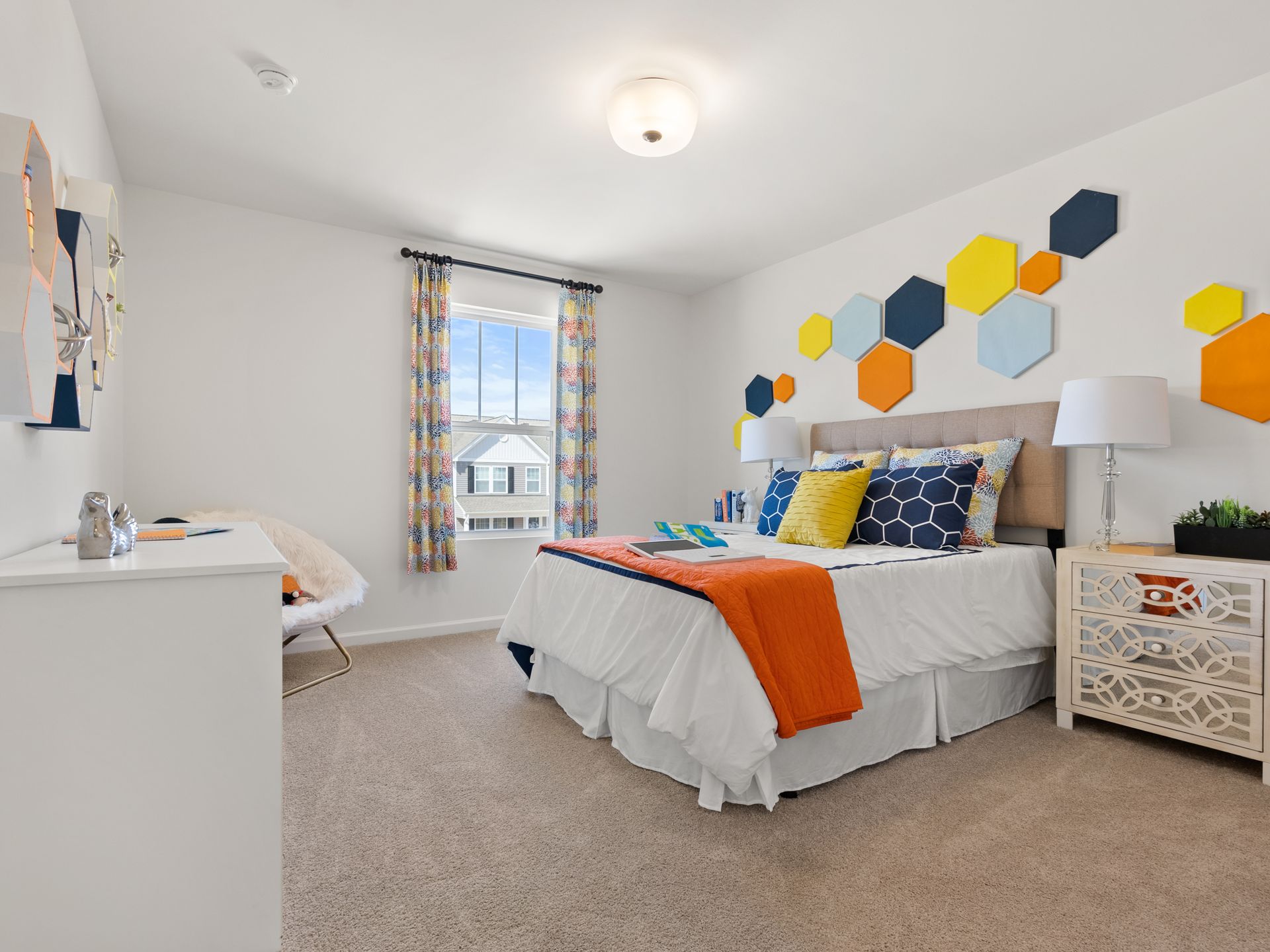 A bedroom with a bed , dresser , nightstand and window.