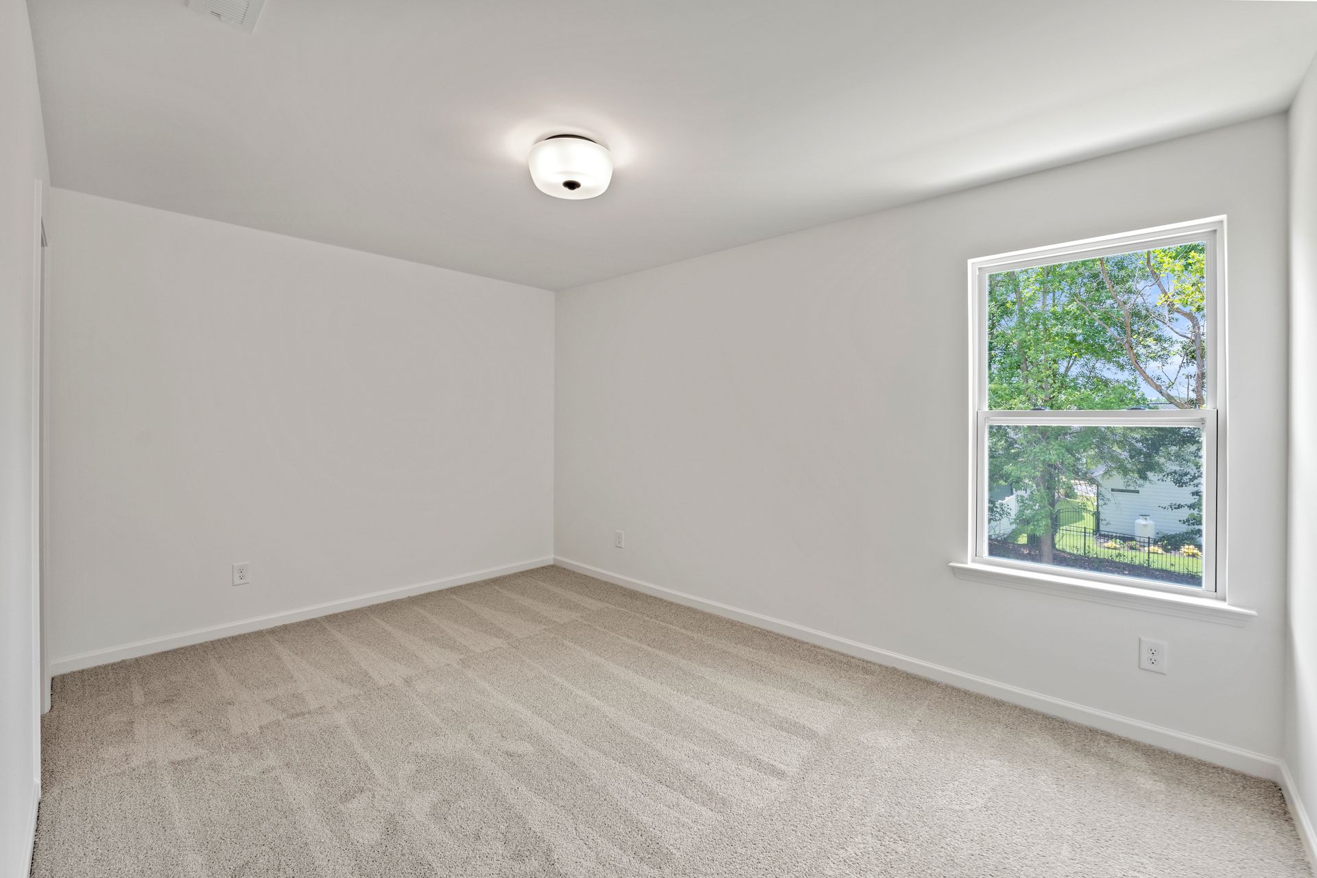 An empty bedroom with a window and carpet.