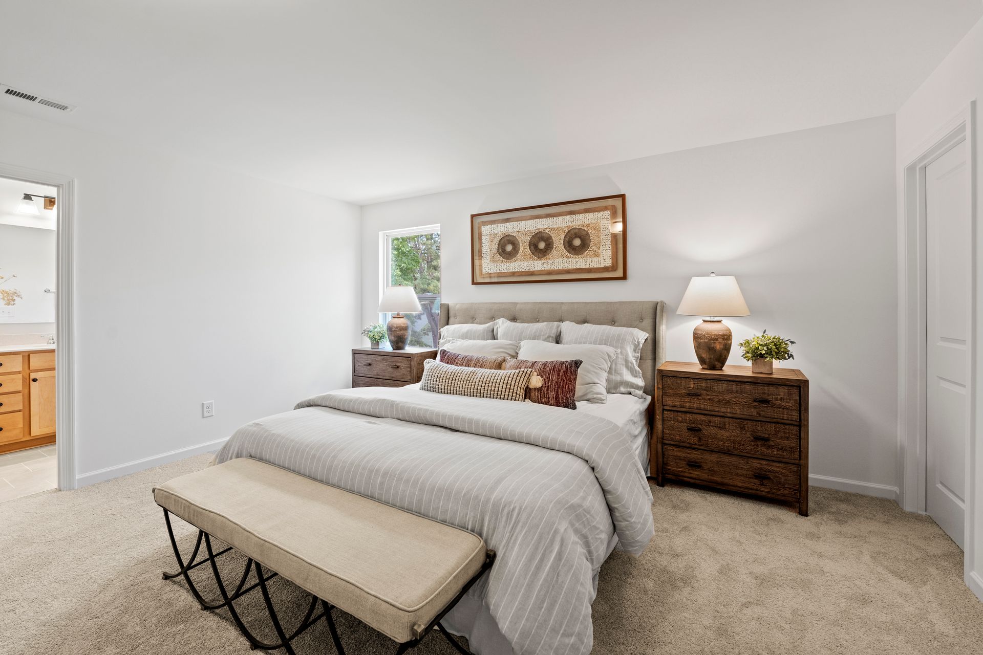 A bedroom with a bed , dresser , nightstand and bench.