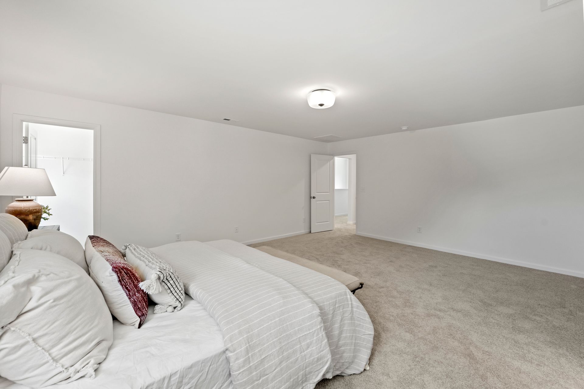 A bedroom with two beds , a lamp and a door.