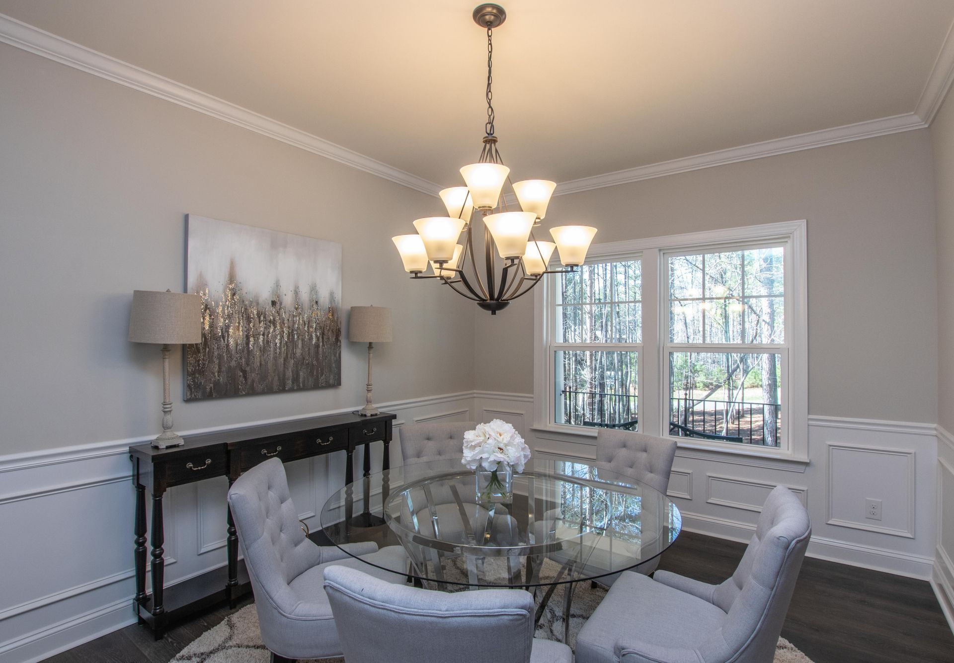 A dining room with a glass table and chairs and a chandelier hanging from the ceiling.