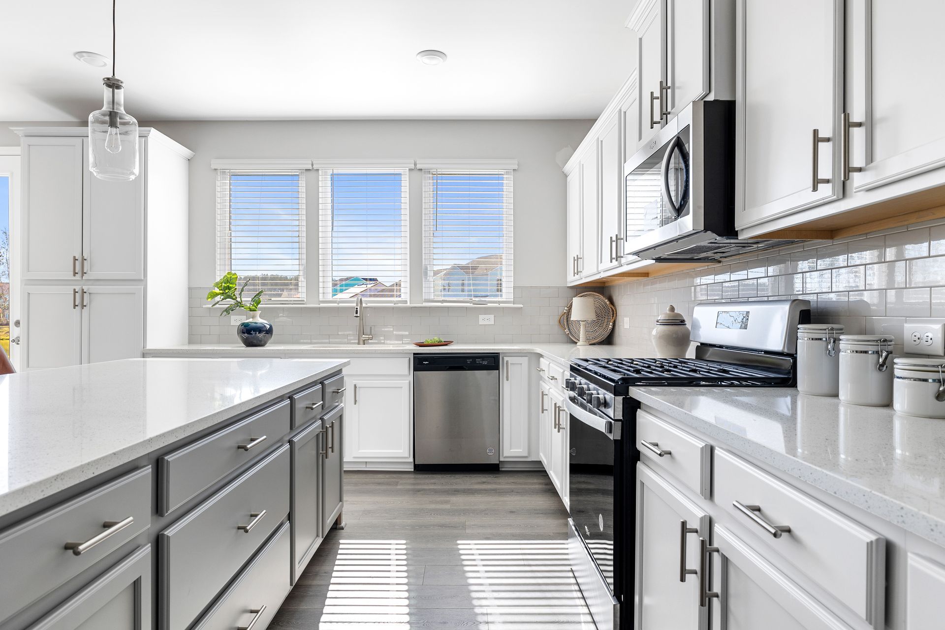 A kitchen with white cabinets , stainless steel appliances , and a large island.