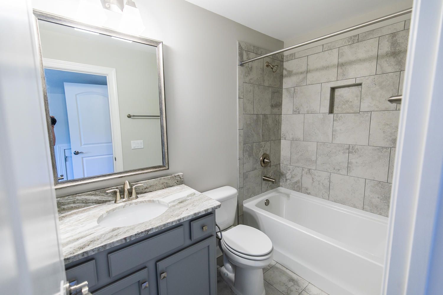 A bathroom with a toilet , sink , tub and mirror.